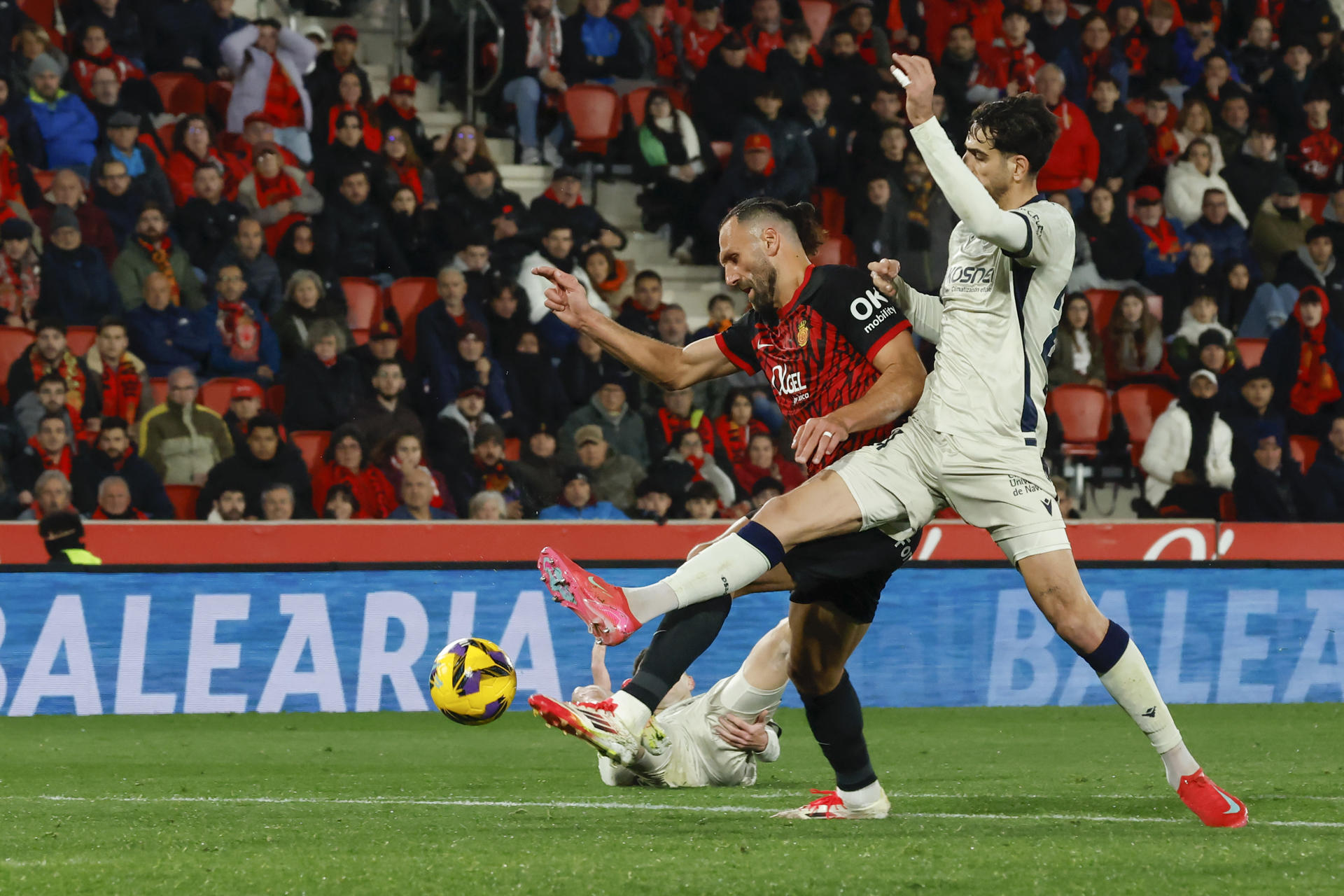 El delantero kosovar del RCD Mallorca, Vedat Muriqi (i), protege el balón ante el centrocampista de Osasuna, Alejandro Catena, en la jugada que ha significado el penalti a favor del equipo mallorquín durante el encuentro correspondiente a la jornada 23 de Laliga EA Sports que disputaron RCD Mallorca y Osasuna en el estadio de Son Moix, en la capital balear. EFE/CATI CLADERA.