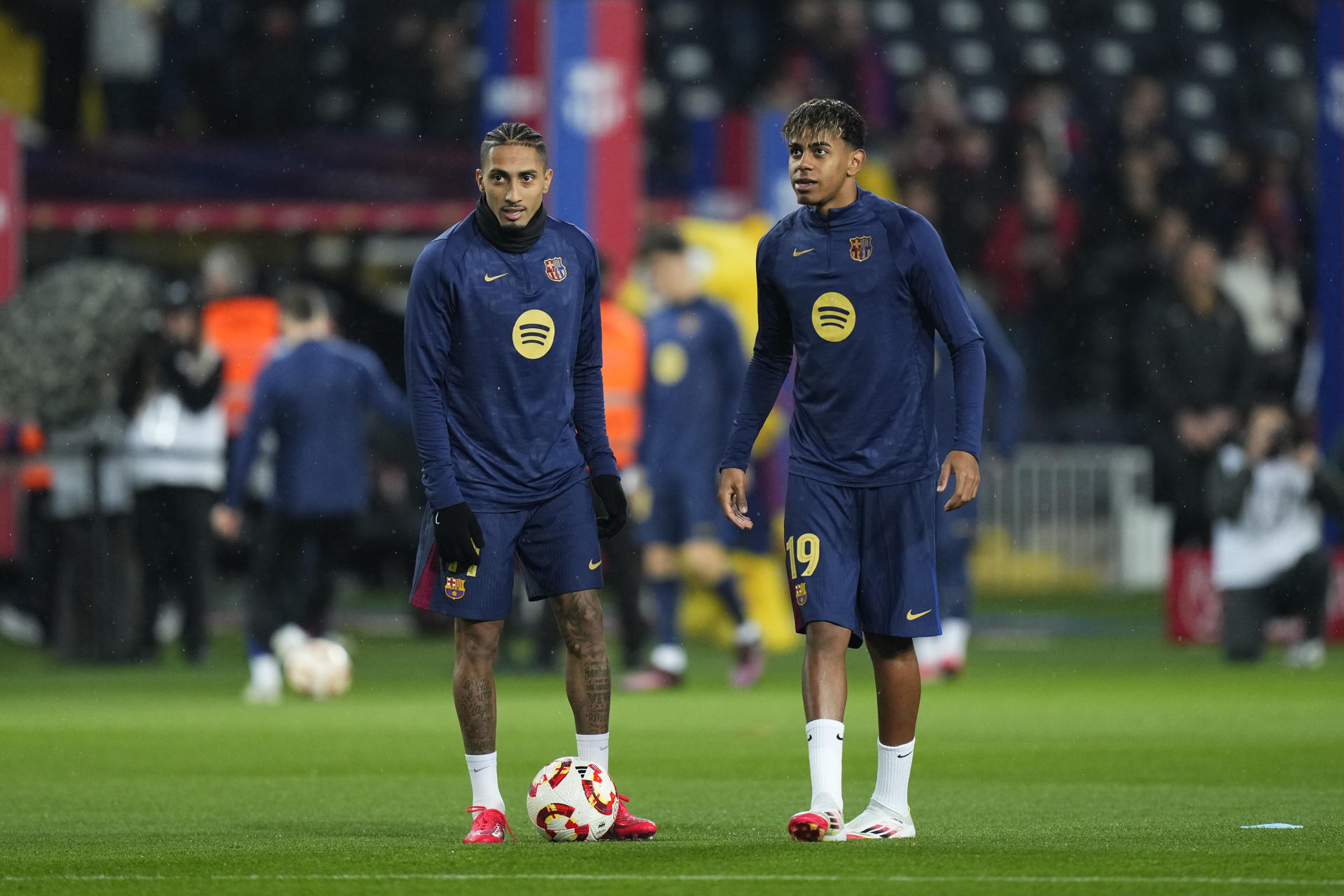 Los delanteros del Barcelona Raphinha (i) y Lamine Yamal, durante el calentamiento previo al partido de ida de las semifinales de la Copa del Rey que FC Barcelona y Atlético de Madrid disputan en el estadio Olímpico Lluis Companys. EFE/Siu Wu