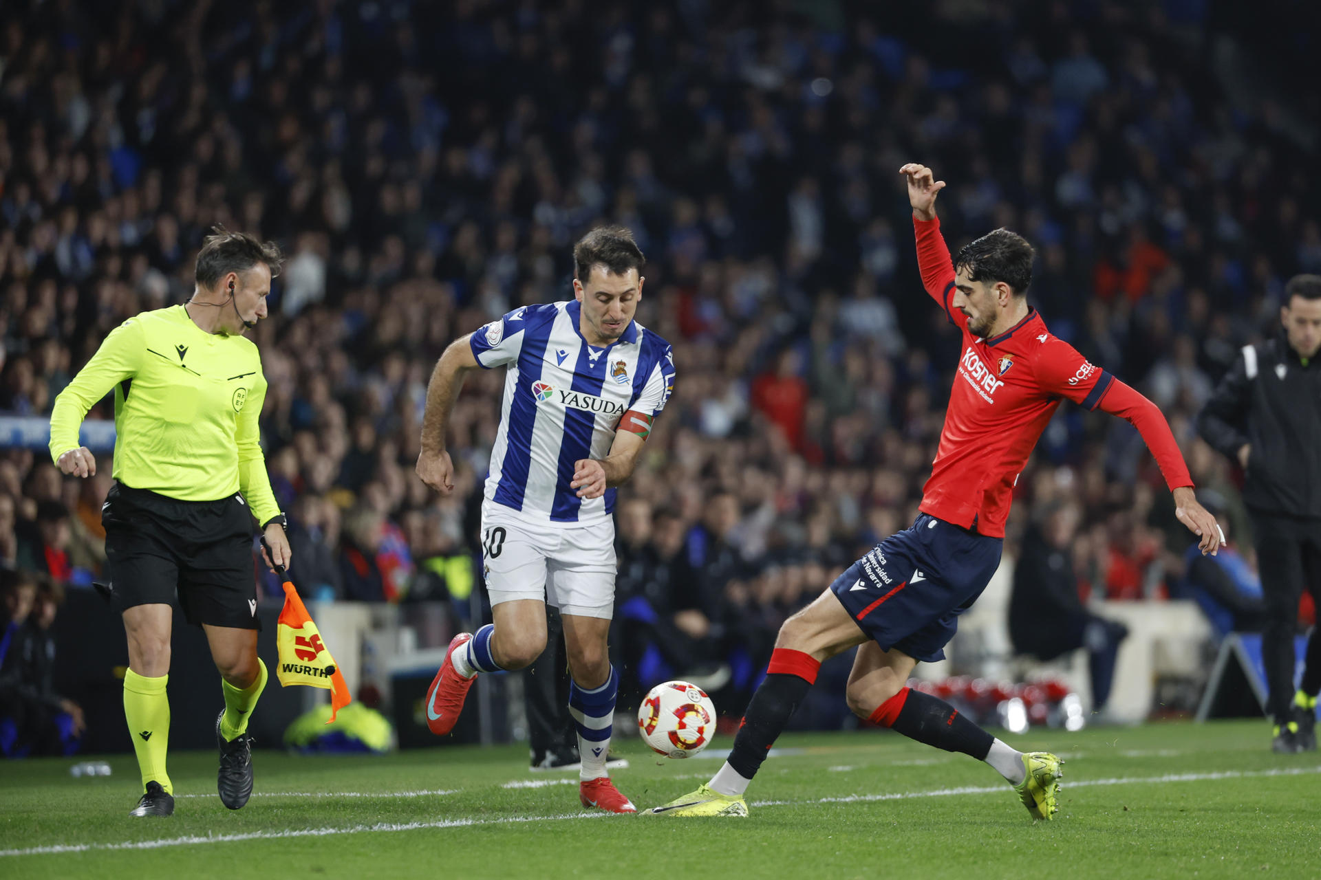El delantero de la Real Sociedad Mikel Oyarzabal (c) disputa un balón con el defensa del Osasuna Alejandro Catena (d) durante el partido de cuartos de final de la Copa del Rey que ambos equipos disputan este jueves en el Reale Arena de San Sebastián. EFE/ Javier Etxezarreta