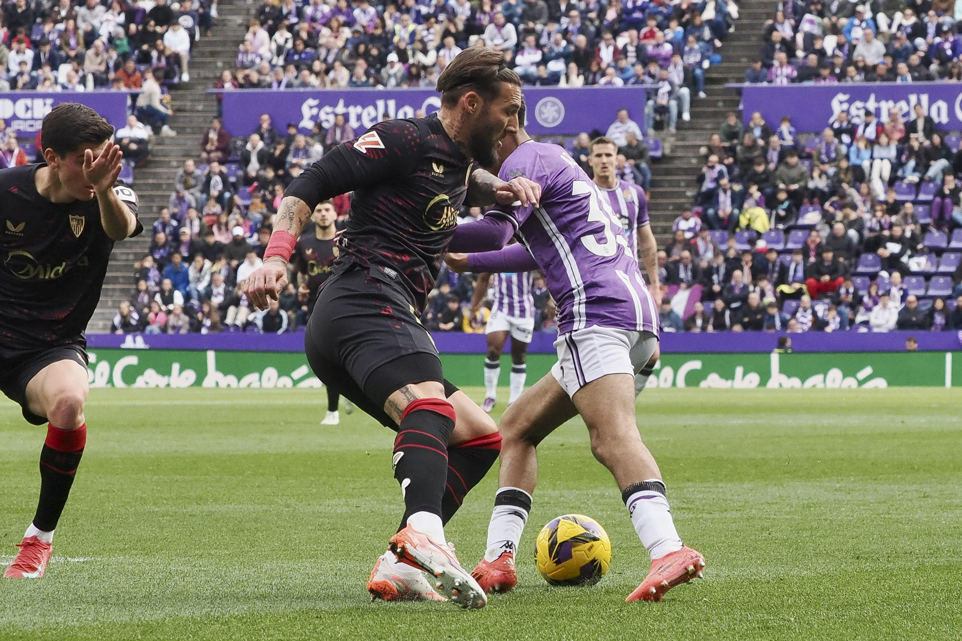 El centrocampista del Valladolid Adam Aznou (d), y el defensa del Sevilla Nemanja Gudelj (c), durante el partido de la jornada 24 de LaLiga EA Sports entre el Valladolid y el Sevilla, este domingo en el estadio José Zorrila.-EFE/R. García