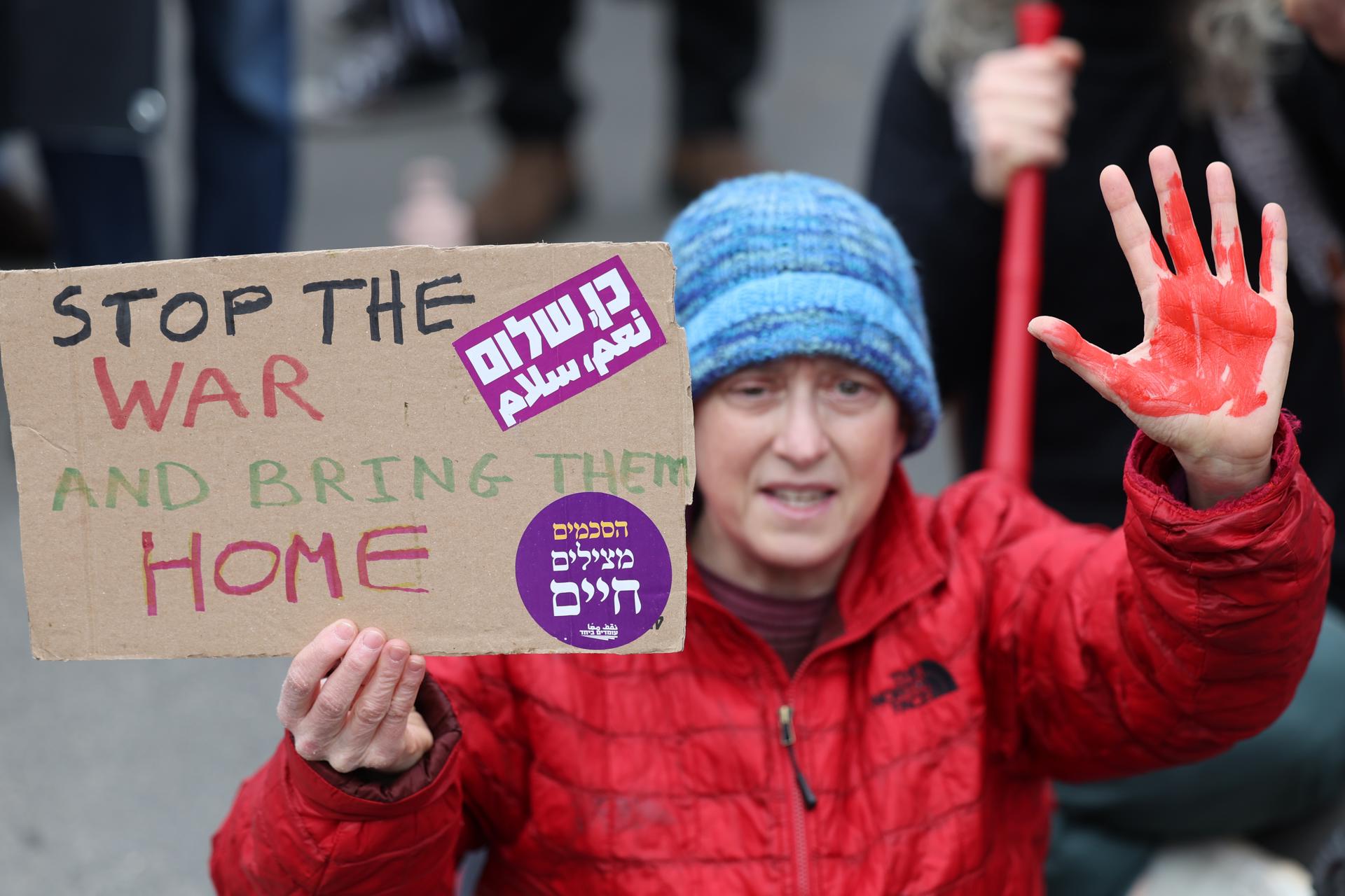 Una manifestante con pintura roja en las manos sostiene un cartel mientras las familias de los rehenes israelíes retenidos por Hamas en Gaza y sus simpatizantes protestan frente a la oficina del Primer Ministro israelí en Jerusalén, el 11 de febrero de 2025, pidiendo la liberación inmediata de los rehenes en medio de un acuerdo de liberación de rehenes y alto el fuego entre Israel y Hamas. (Protests, Jerusalem) 
EFE/EPA/ABIR SULTAN