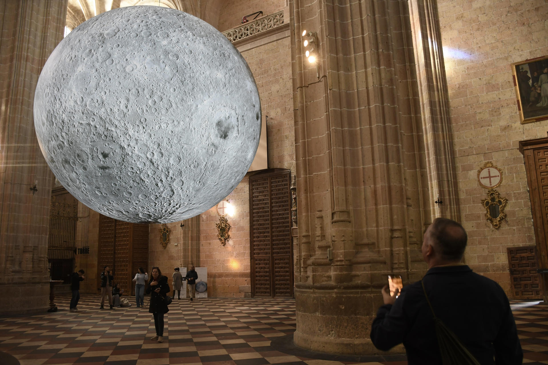 La catedral de Segovia se ha convertido en la primera parada española de la exposición 'Museum of the Moon', del artista británico Luke Jerram, una muestra que podrá visitarse hasta el próximo 31 de marzo en el trascoro del templo. Suspendida a cuatro metros del suelo, la instalación permite al visitante contemplar la representación del satélite terrestre a una escala aproximada de 1:500.000. EFE/ Pablo Martin