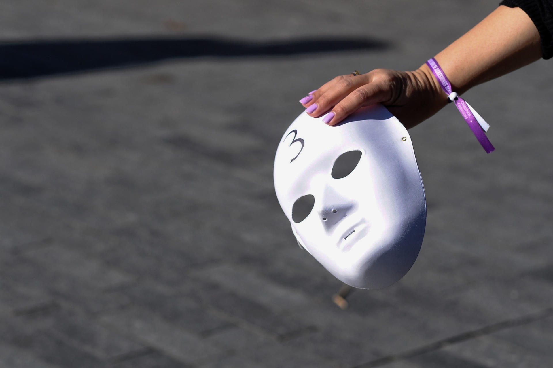 Imagen de archivo de una mujer sosteniendo una careta durante una concentración del Día Internacional de la Eliminación de la Violencia Contra la Mujer. EFE/Nacho Gallego