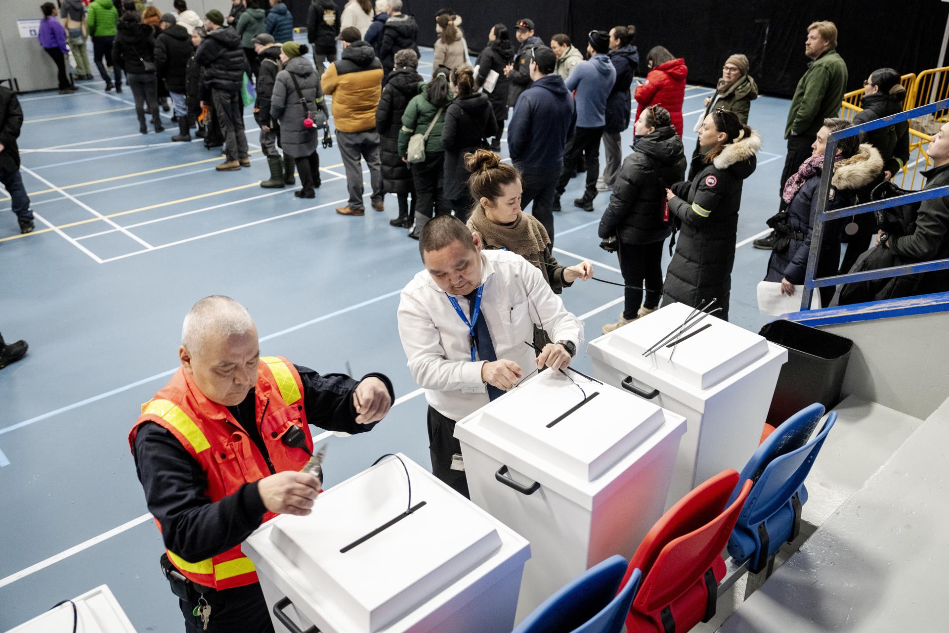 Funcionarios electorales (i) fueron registrados este martes, 11 de marzo, al preparar unas urnas antes de que decenas de ciudadanos puedan votar, en el polideportivo Godthaabshallen, en la ciudad de Nuuk, durante las elecciones generales en Groenlandia. EFE/Mads Claus Rasmussen