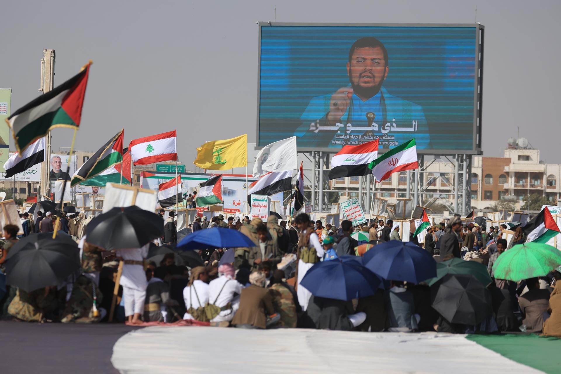 Foto de archivo que muestra a partidarios hutíes agitan las banderas del eje de resistencia respaldado por Irán frente a una valla publicitaria digital con la imagen del líder de los hutíes, Abdul-Malik al-Houthi, durante una protesta contra la política del presidente de EE.UU., Donald Trump, sobre Gaza, en Saná, Yemen. EFE/EPA/YAHYA ARHAB