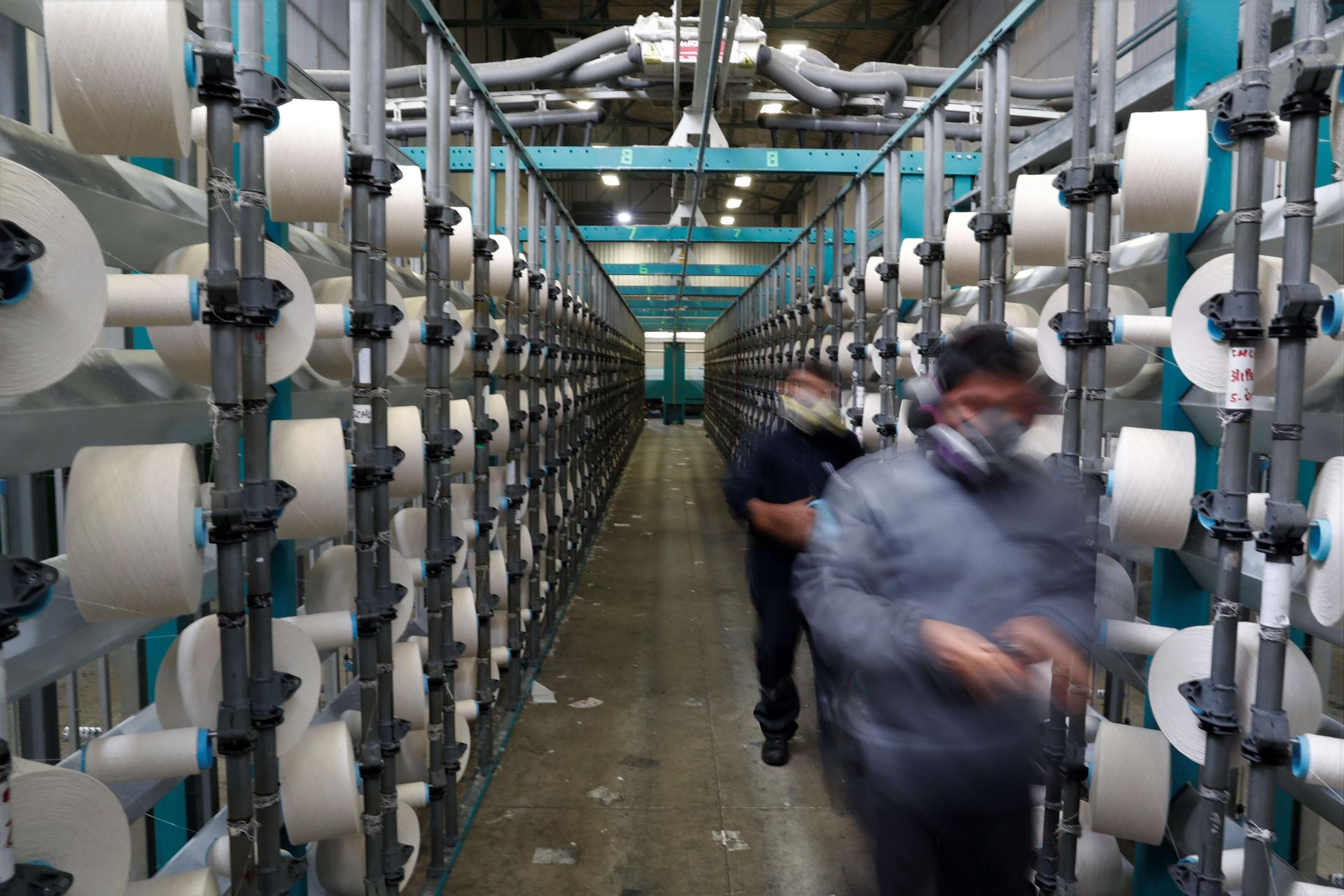 Fotografía de archivo en la que se registró a un par de operarios en una de las líneas de producción de la fábrica de telas Nuevo Mundo, en Lima (Perú). EFE/Paolo Aguilar