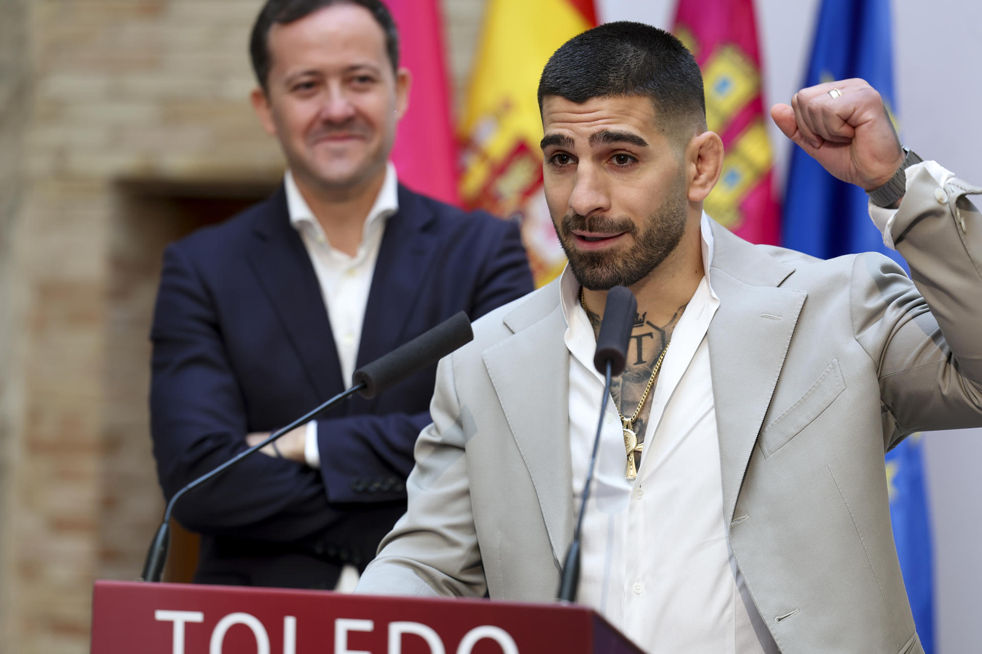 El actual campeón del mundo de peso pluma, Ilia Topuria, (dch), ante el alcalde de Toledo, Carlos Velázquez, interviene en la inauguración del pabellón de San Lázar, en Toledo, este martes. EFE/ Ismael Herrero