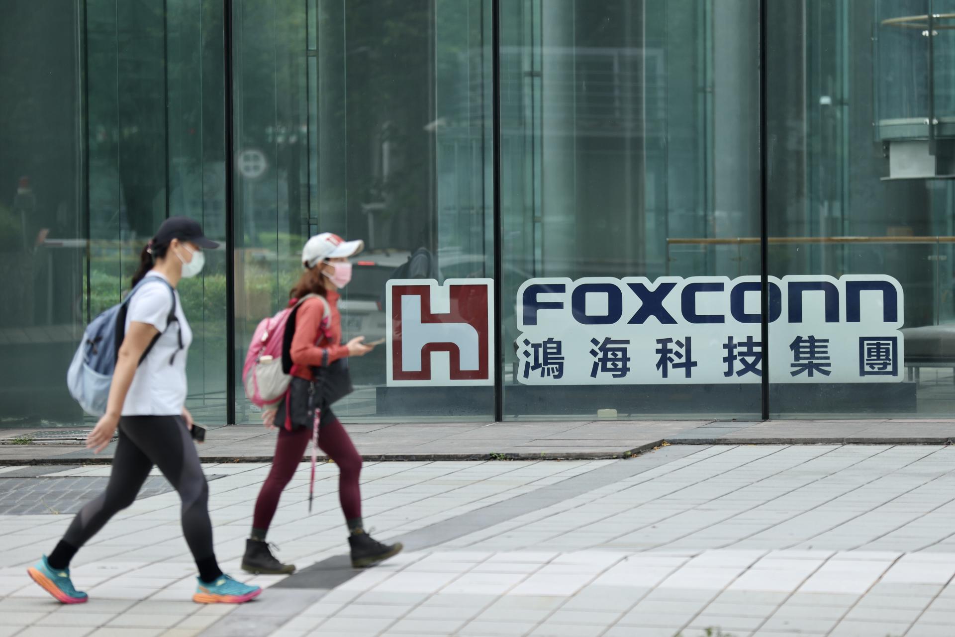 Fotografía de archivo fechada el 22 de octubre de 2023 que muestra personas caminando junto al logotipo de la compañía Foxconn en Taipei, Taiwán. EFE/Ritchie B. Tongo
