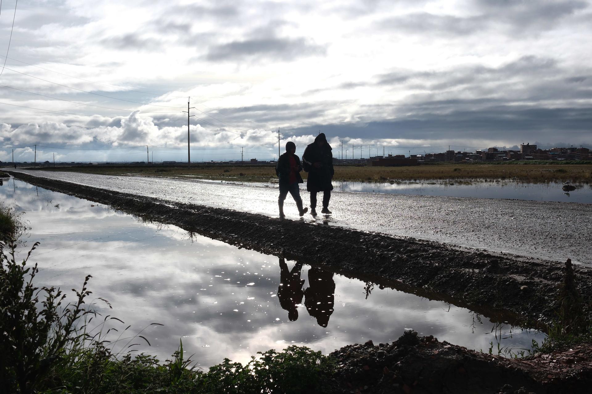 Personas caminan por una vía afectada por fuertes lluvias este 14 de marzo de 2025 en Viacha (Bolivia). EFE/ Luis Gandarillas