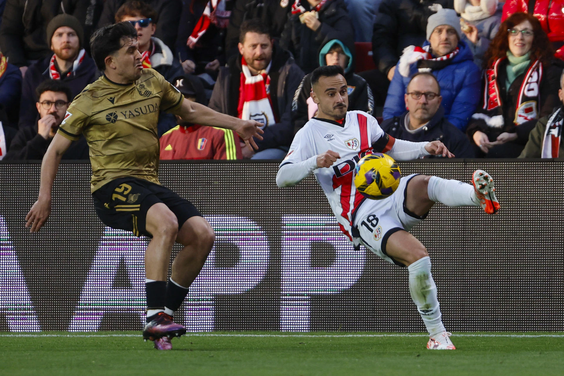 El centrocampista del Rayo Vallecano, Álvaro García (d), golpea el balón ante el defensa de la Real Sociedad, Jon Aramburu, durante el encuentro correspondiente a la jornada 28 de Laliga EA Sports en el estadio de Vallecas, en Madrid. EFE / Sergio Perez.