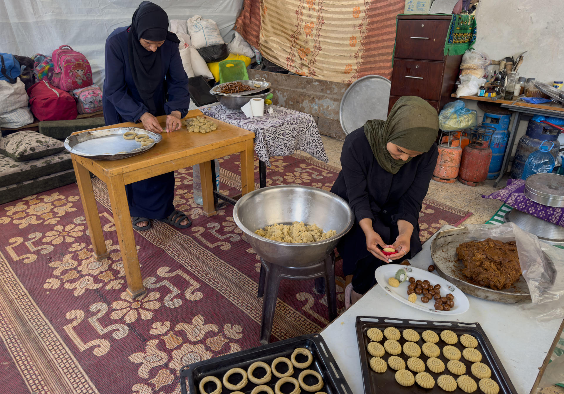 Amal Joud Kilani, una mujer gazatí de 58 años, que hasta en cinco ocasiones ha sido desplazada del norte de la Franja por los bombardeos israelíes, ha querido seguir con la tradición de preparar los dulces típicos del fin de este "triste" Ramadán que finaliza este domingo, aunque ahora los cocina en los bajos de un edificio en ruinas recurriendo a un rústico horno de leña. Antes de la guerra, Amal trabajaba en Beit Lahia (norte) en una cooperativa de mujeres que regentaba una pastelería, pero los ataques israelíes la obligaron a desplazarse al sur. Con el último alto el fuego, al igual que decenas de miles de gazatíes, volvió al norte para encontrarse con su casa completamente destrozada. 
EFE/Ahmad Awad