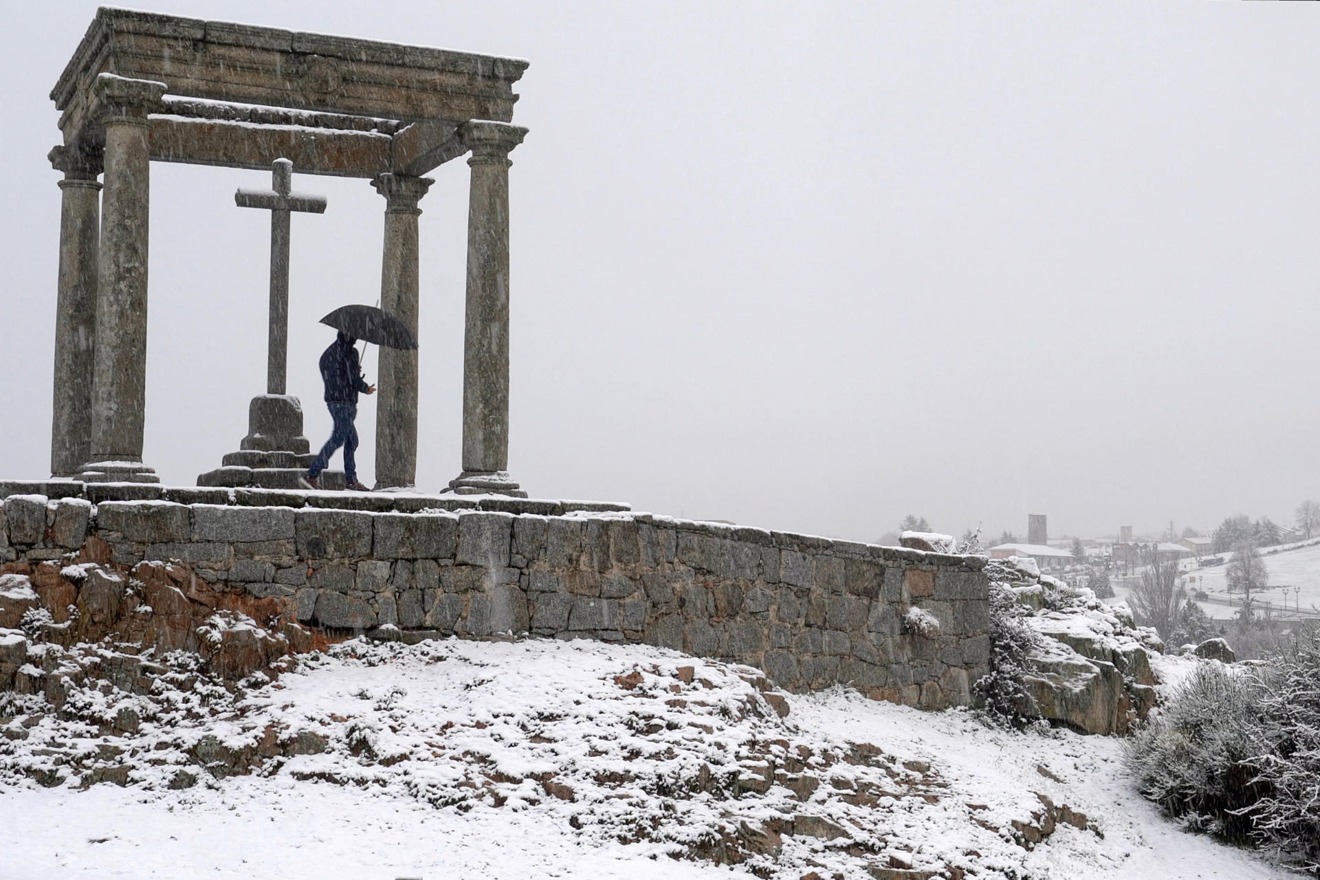 Un hombre camina en un paraje cubierto de nieve en los alrededores de la ciudad de Ávila, este domingo. Tras las inundaciones y los problemas causados hace una semana por el paso de la borrasca 'Jana', este domingo Ávila se ha despertado cubierta de un manto blanco, tras la nevada que ha caído sobre la capital y buena parte de la provincia en las últimas horas. EFE/ Raúl Sanchidrián