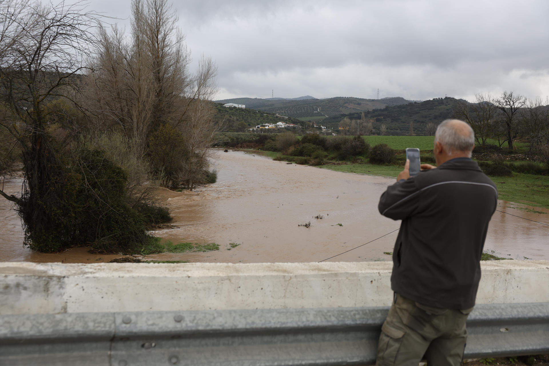 Un hombre fotografía el río Turón a su paso por el Burgo (Málaga). La Junta de Andalucía ha elevado el plan de riesgo de inundaciones a fase de emergencia por la evolución de las previsiones, ya que la Aemet ha subido a rojo el aviso por fuertes lluvias en la Serranía de Ronda (Málaga). EFE/Jorge Zapata
