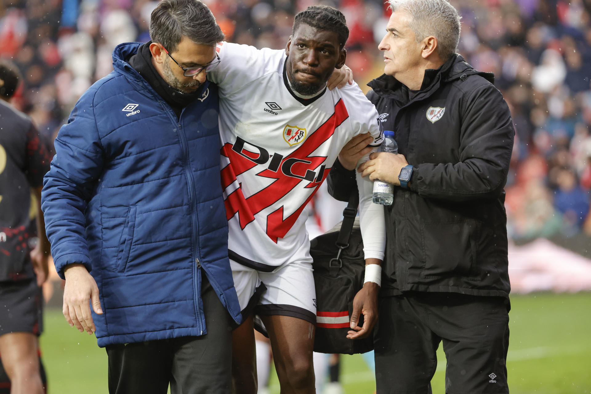 El delantero francés del Rayo Vallecano Randy Nteka (c) sale lesionado este sábado, en el partido de la jornada 26 de LaLiga EA Sports, entre el Rayo Vallecano y el Sevilla FC, en el estadio de Vallecas, en Madrid. EFE/ Zipi Aragón
