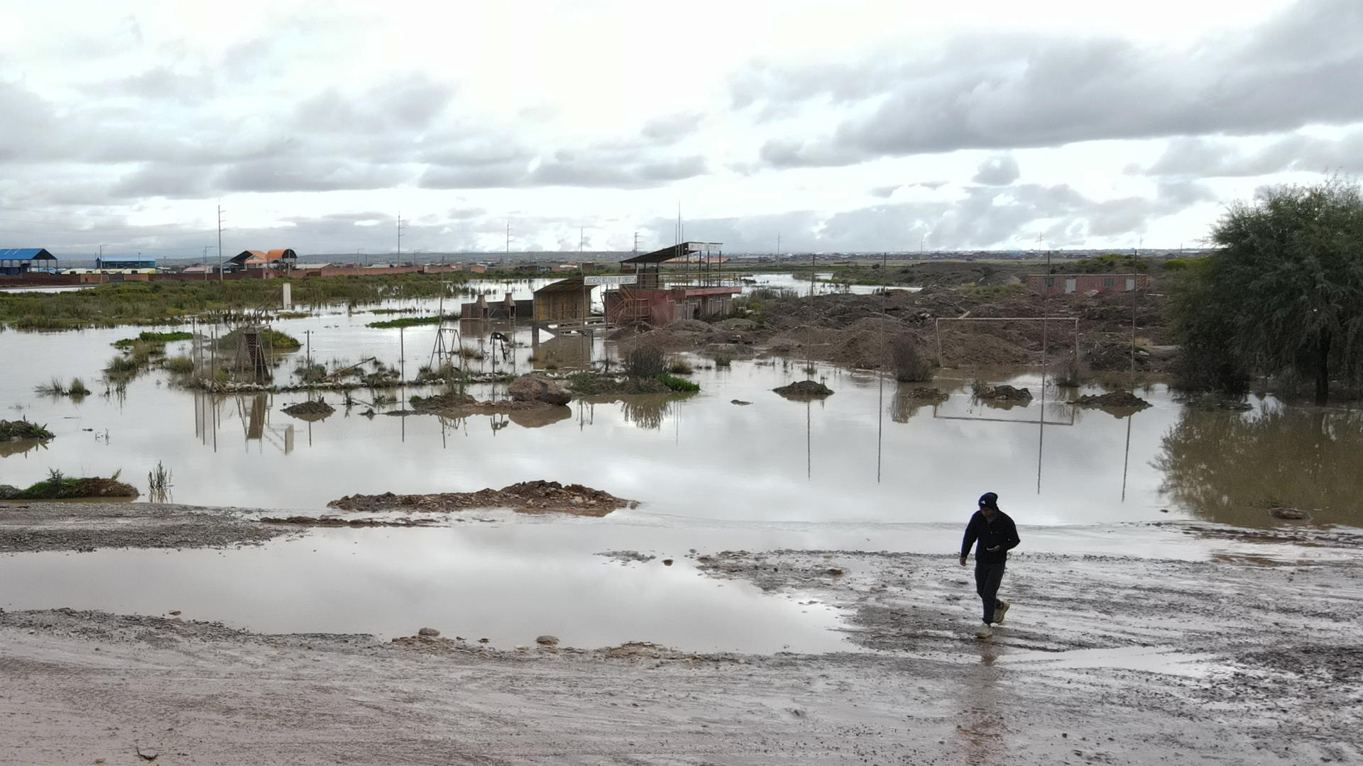 Una persona camina por una cancha de fútbol afectada por fuertes lluvias este 14 de marzo de 2025, en Viacha (Bolivia). EFE/ Luis Gandarillas