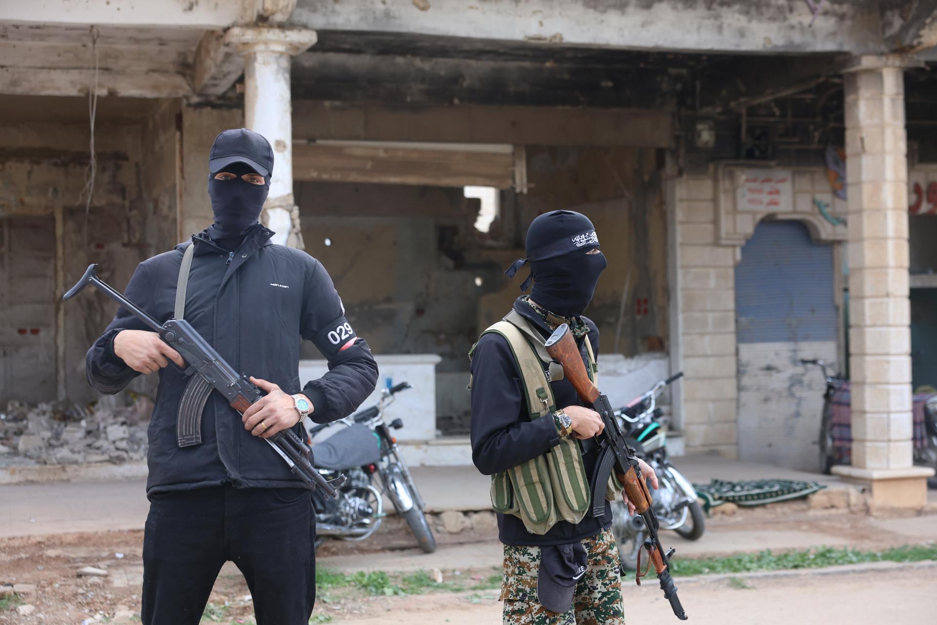 Miembros de seguridad sirios hacen guardia cerca de edificios dañados un día después de que un ataque aéreo israelí golpeara la ciudad de Deraa, en el sur de Siria, el 18 de marzo de 2025. EFE/EPA/MOHAMMED AL RIFAI