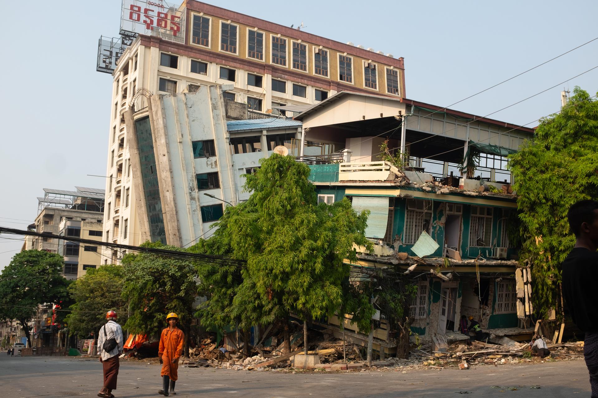 Un par de rescatistas fue registrado este sábado, 29 de marzo, al caminar frente a un edificio afectado por el terremoto de magnitud 7.7 que azotó el viernes a Birmania, en la ciudad de Mandalay. EFE/Stringer