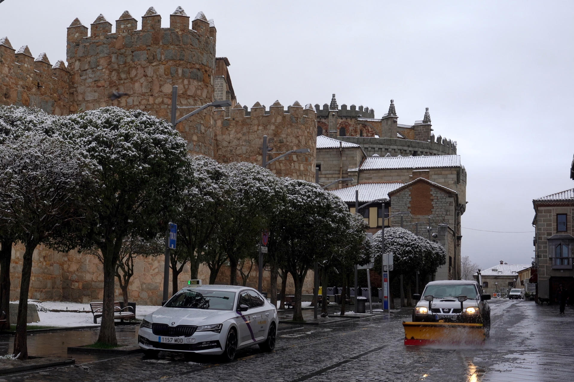 Un vehículo quitanieves limpia una calle colindente a las murallas de Ávila, este domingo. Tras las inundaciones y los problemas causados hace una semana por el paso de la borrasca 'Jana', este domingo Ávila se ha despertado cubierta de un manto blanco, tras la nevada que ha caído sobre la capital y buena parte de la provincia en las últimas horas. EFE/ Raúl Sanchidrián
