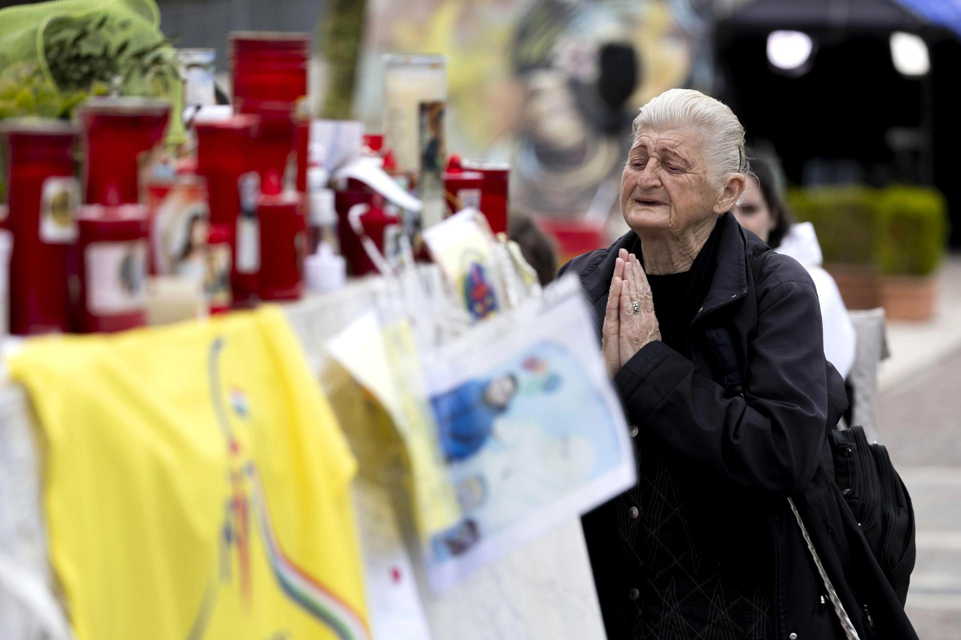 Una persona mayor reza junto a velas por el Papa Francisco en la estatua del Papa Juan Pablo II, frente al Hospital Gemelli, en Roma, Italia, 12 de marzo de 2025. El Papa Francisco ha estado hospitalizado en el Hospital Gemelli de Roma desde el 14 de febrero de 2025, debido a una infección del tracto respiratorio. (Papa, Italia, Roma) EFE/EPA/MASSIMO PERCOSSI