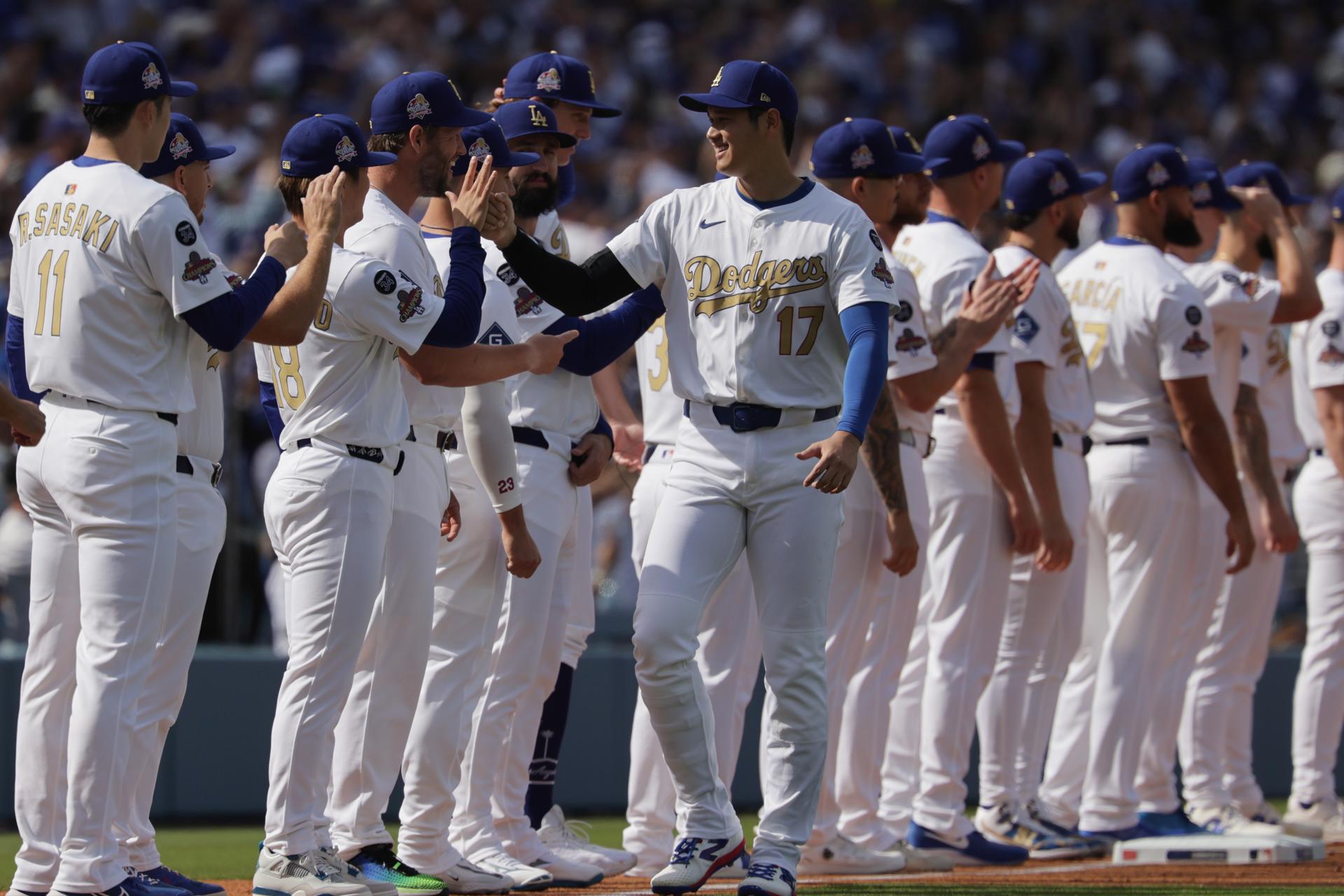 Shohei Ohtani saluda a sus compañeros de los Angeles Dodgers, defensores de la Serie Mundial de béisbol, en el partido de de inicio de la temporada de las Grandes Ligas ante los Detroits Tigers este jueves. EFE/ALLISON DINNER