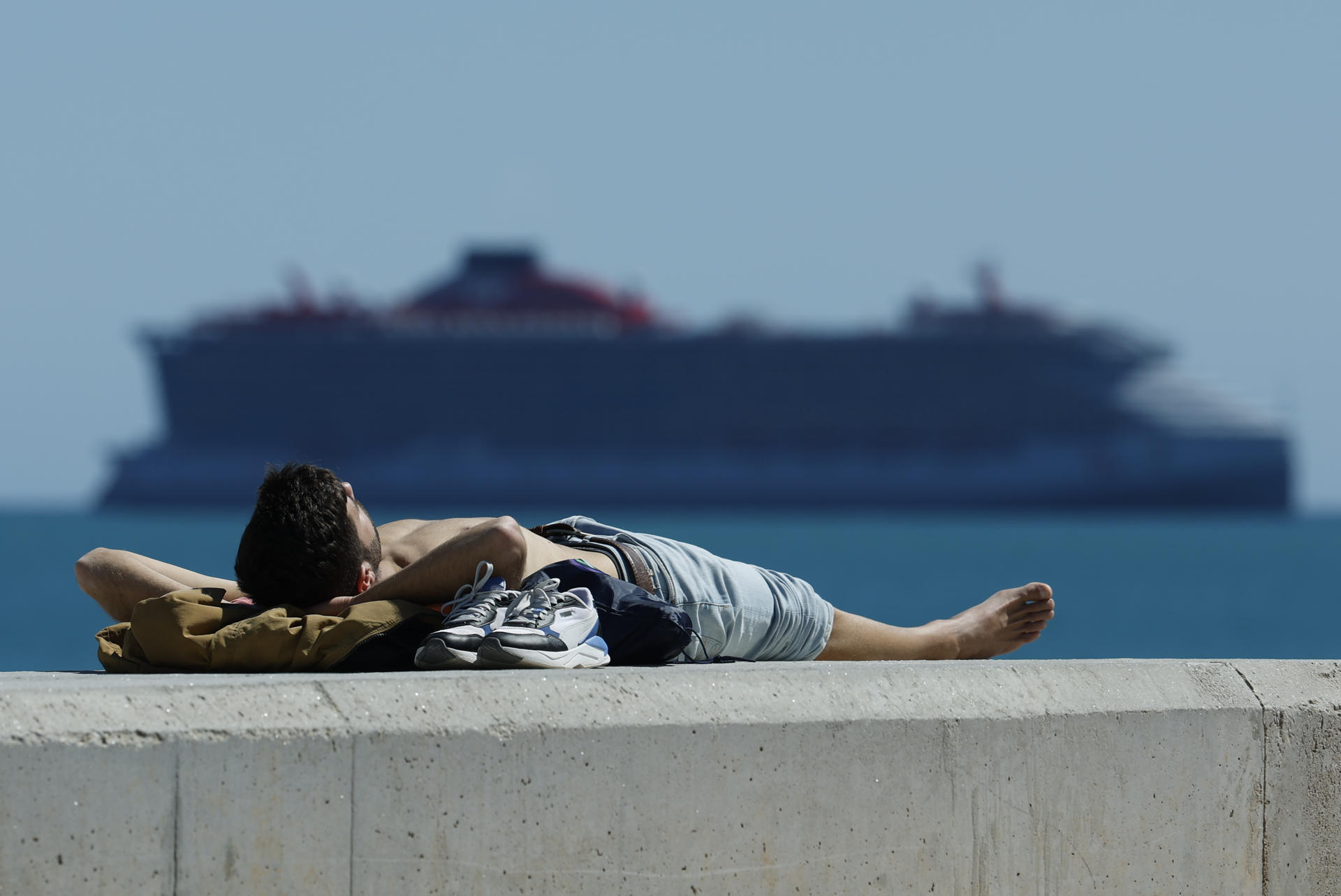MÁLAGA, 24/03/2025.- Una persona toma el sol con el buen tiempo el pasado lunes en el puerto de Málaga. EFE/Jorge Zapata