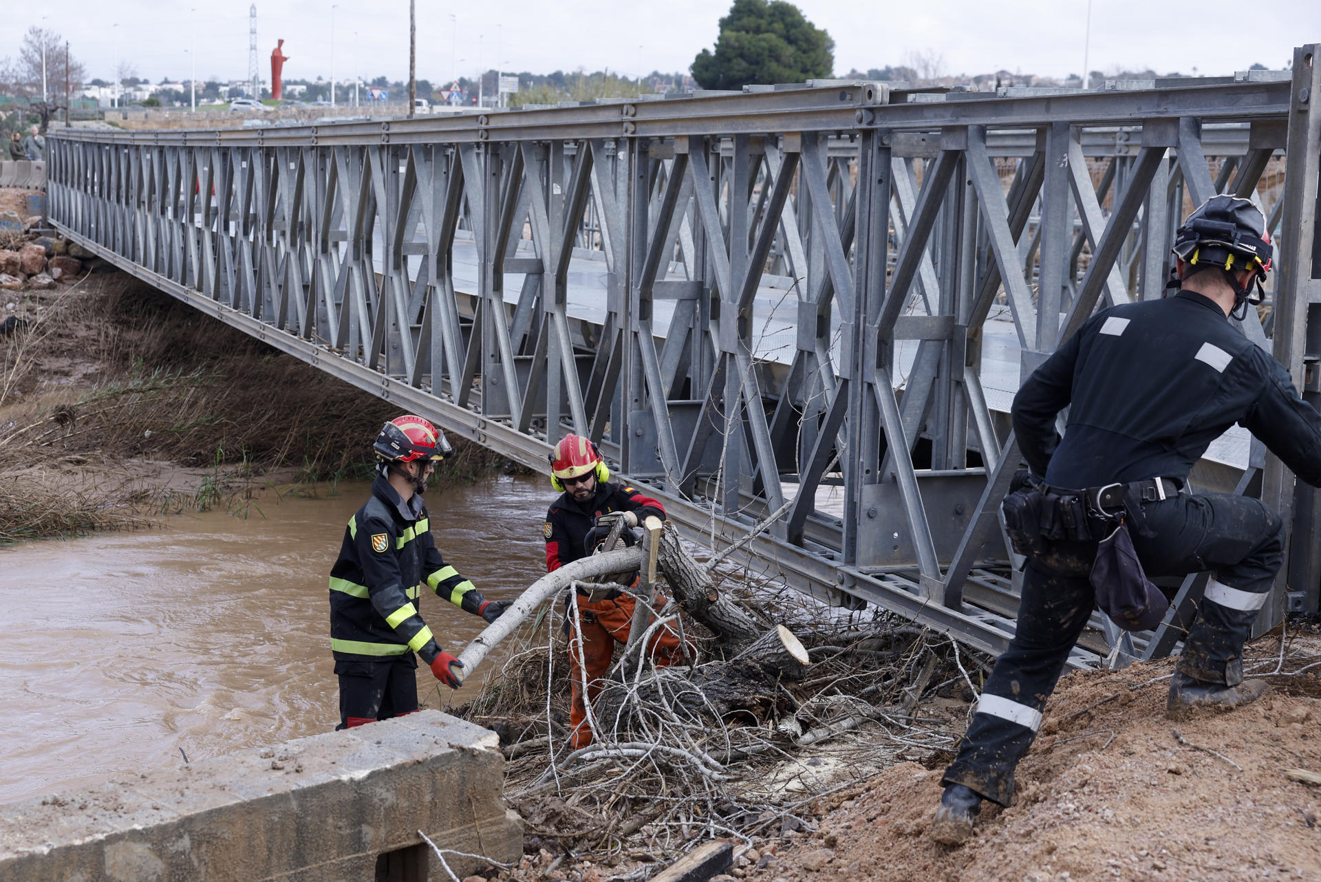 GRAFCVA5951. RIBARROJA DEL TURIA (VALENCIA), 04/03/2025.- Miembros de la Unidad Militar de Emergencias (UME) despejan troncos en el puente provisional militar que cruza el cauce del río Turia en la carretera cuando varias carreteras de las provincias de Valencia y Castellón permanecen cortadas debido a la lluvia. EFE/Kai Försterling