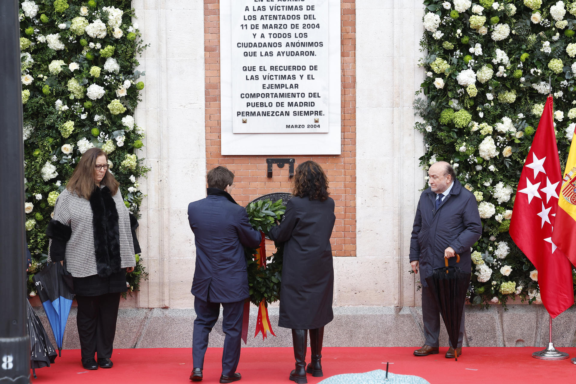 La presidenta de la Comunidad de Madrid, Isabel Díaz Ayuso (2d), y el alcalde de la capital, José Luis Martínez-Almeida (2i), colocan una corona bajo la placa conmemorativa a las víctimas de los atentados del 11 de marzo de 2004 en la fachada de la sede del Gobierno de la Comunidad de Madrid, este martes, cuando se cumplen 21 años del suceso. EFE/ J. P. Gandul