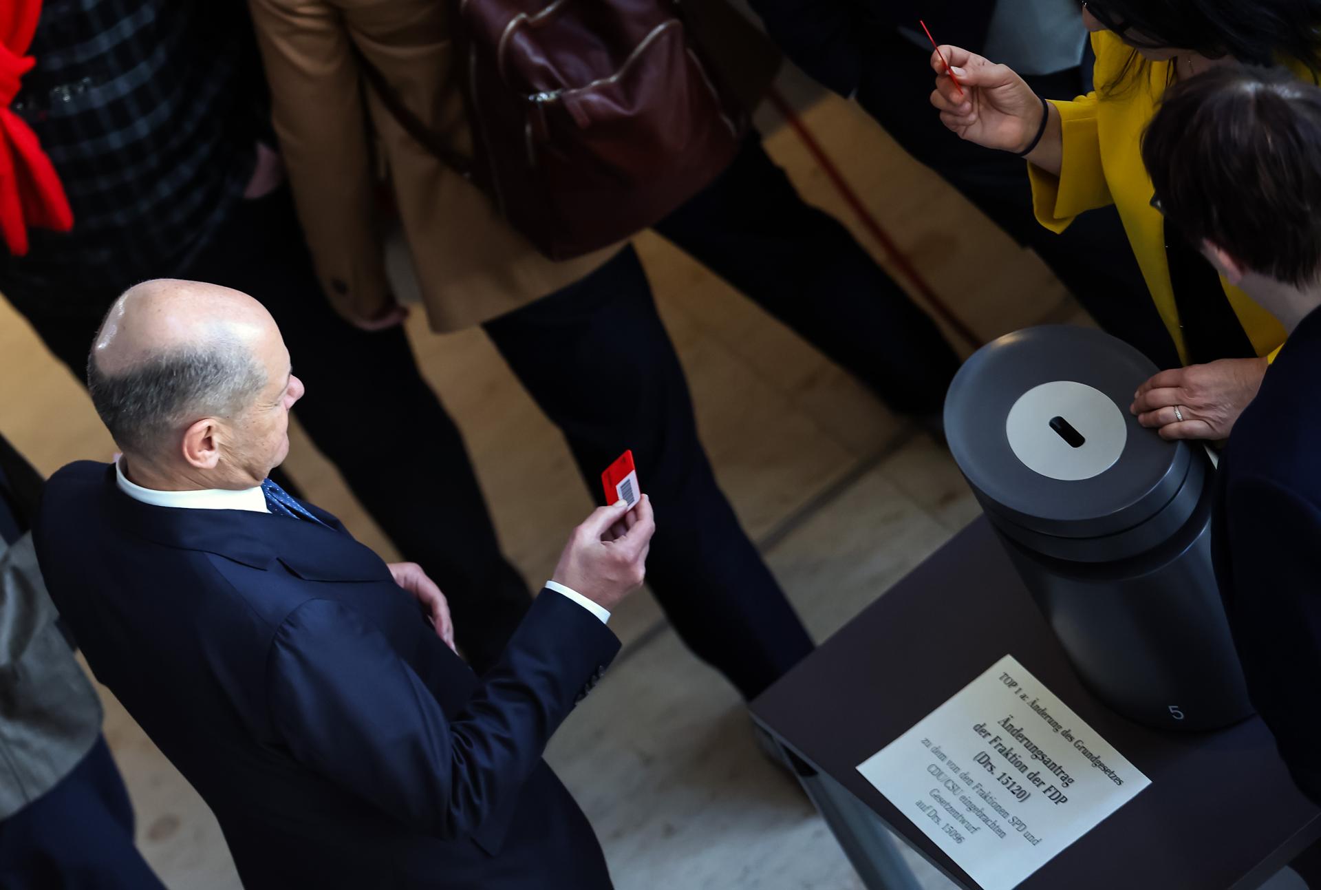 El canciller alemán Olaf Scholz (izquierda) se prepara para emitir su voto durante una sesión plenaria especial del parlamento alemán 'Bundestag', en Berlín, Alemania, 18 de marzo de 2025. El Bundestag alemán está votando un proyecto de ley para facilitar el freno de la deuda para el gasto en defensa, que incluye un fondo de 500 mil millones de euros para inversiones en infraestructura y neutralidad climática. (Germany) EFE/EPA/HANNIBAL HANSCHKE