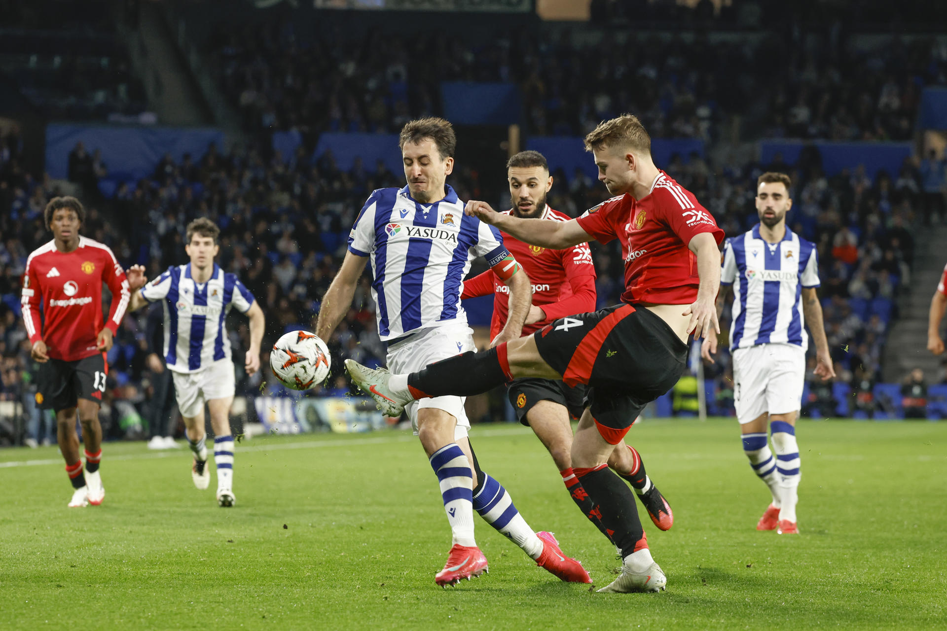 El centrocampista de la Real Sociedad Mikel Oyarzabal (c-i) disputa un balón ante el defensa del Manchester United Matthijs de Ligt este jueves, durante el primer partido de octavos de final de la Liga Europa, que enfrenta a la Real Sociedad y al Manchester United, en el Real Arena de San Sebastián. EFE/ Javier Etxezarreta