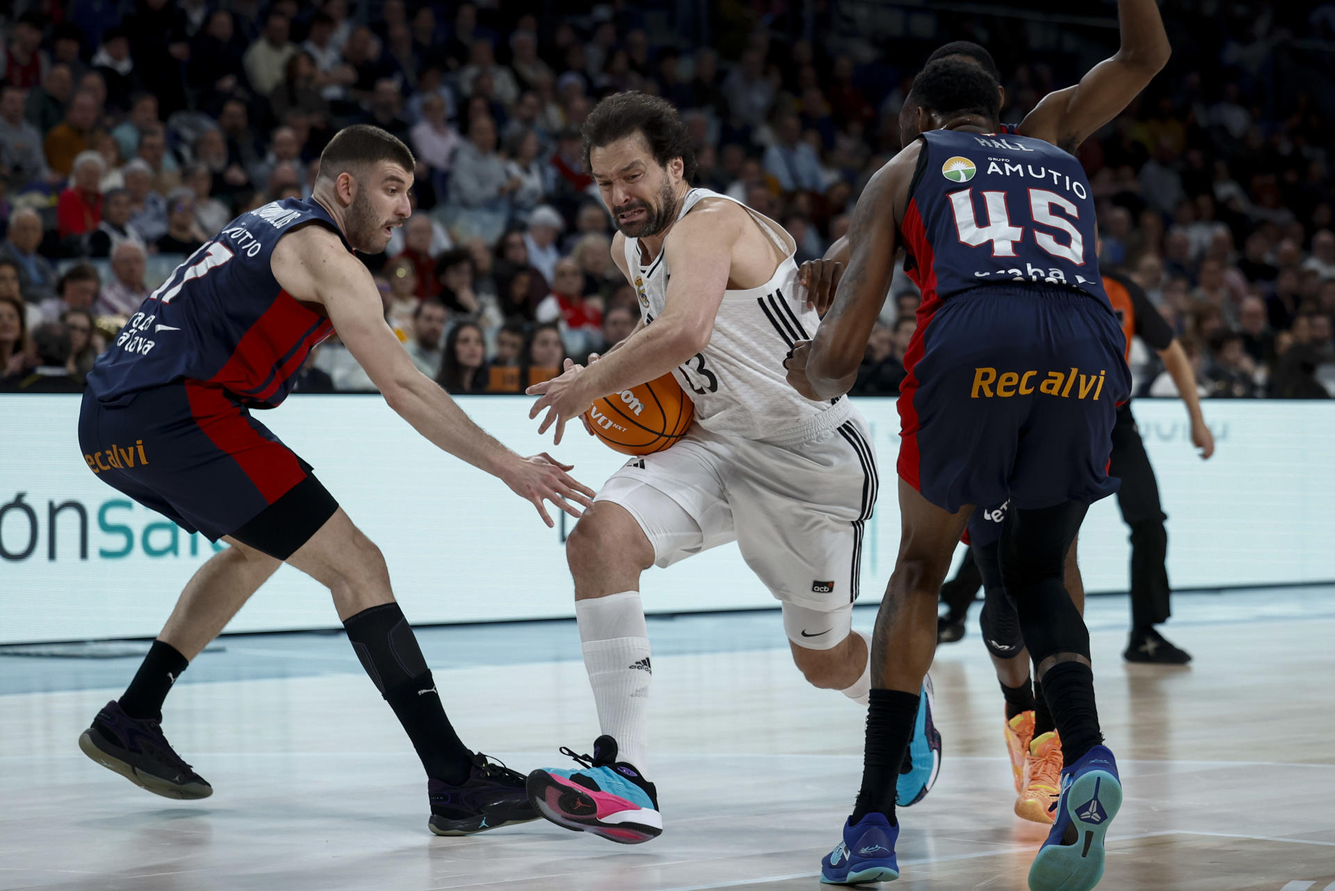 El alero del Real Madrid Sergi Llull (c) con el balón ante los defensores de Baskonia durante el encuentro correspondiente a la fase regular de la Liga Endesa que disputaron Baskonia y Real Madrid en el pabellón Movistar Arena de Madrid. EFE / Daniel González.