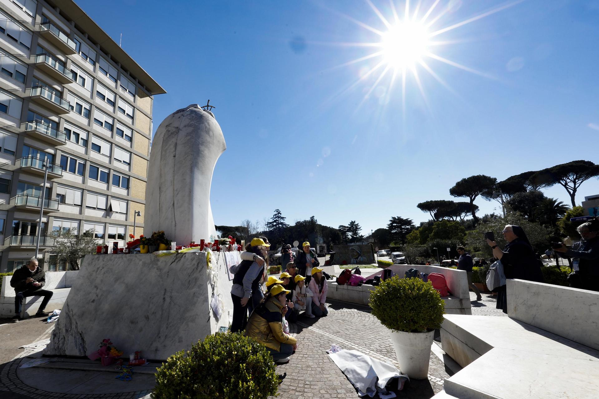 Niños de una escuela primaria en Rivoli, cerca de Turín, rezan frente a la estatua de Juan Pablo II en la entrada del Hospital Gemelli, donde está hospitalizado el Papa Francisco, en Roma, Italia, 18 de marzo de 2025. El Papa Francisco fue ingresado en el Hospital Gemelli de Roma el 14 de febrero debido a una infección del tracto respiratorio. (Papa, Italia, Roma) EFE/EPA/FABIO FRUSTACI