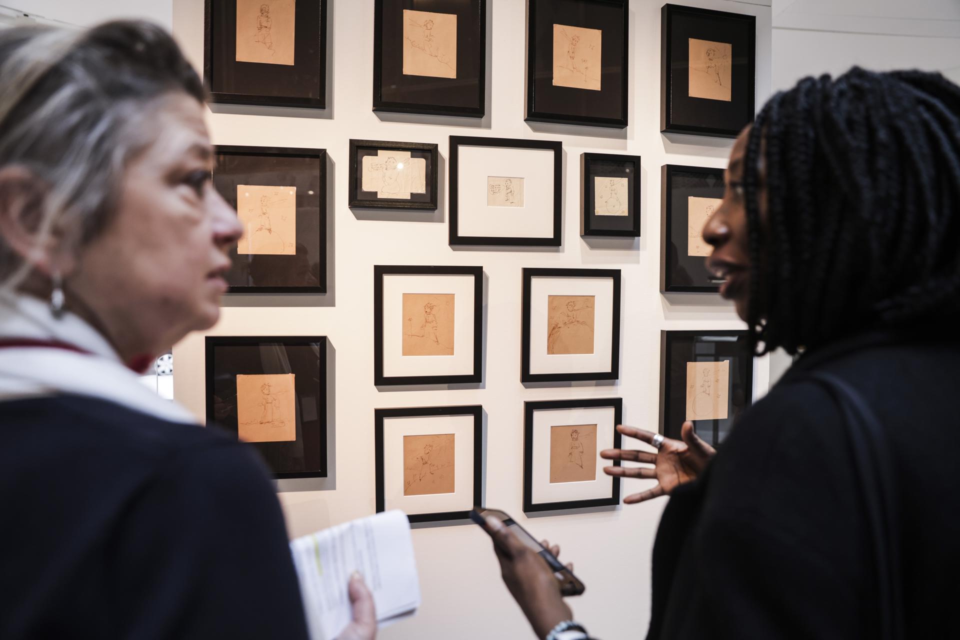 Dos mujeres hablan junto a la colección de 16 ilustraciones originales de 1943 de El Principito de Antoine de Saint-Exupéry, expuestas al público en Sotheby’s en París, Francia, el 25 de marzo de 2025. Ilustraciones de Antoine de Saint-Exupéry, junto con partes del manuscrito original de Aliento de Jean-Luc Godard, serán subastadas entre el 04 de junio y el 18 de junio de 2025.  (Francia) EFE/EPA/TERESA SUAREZ