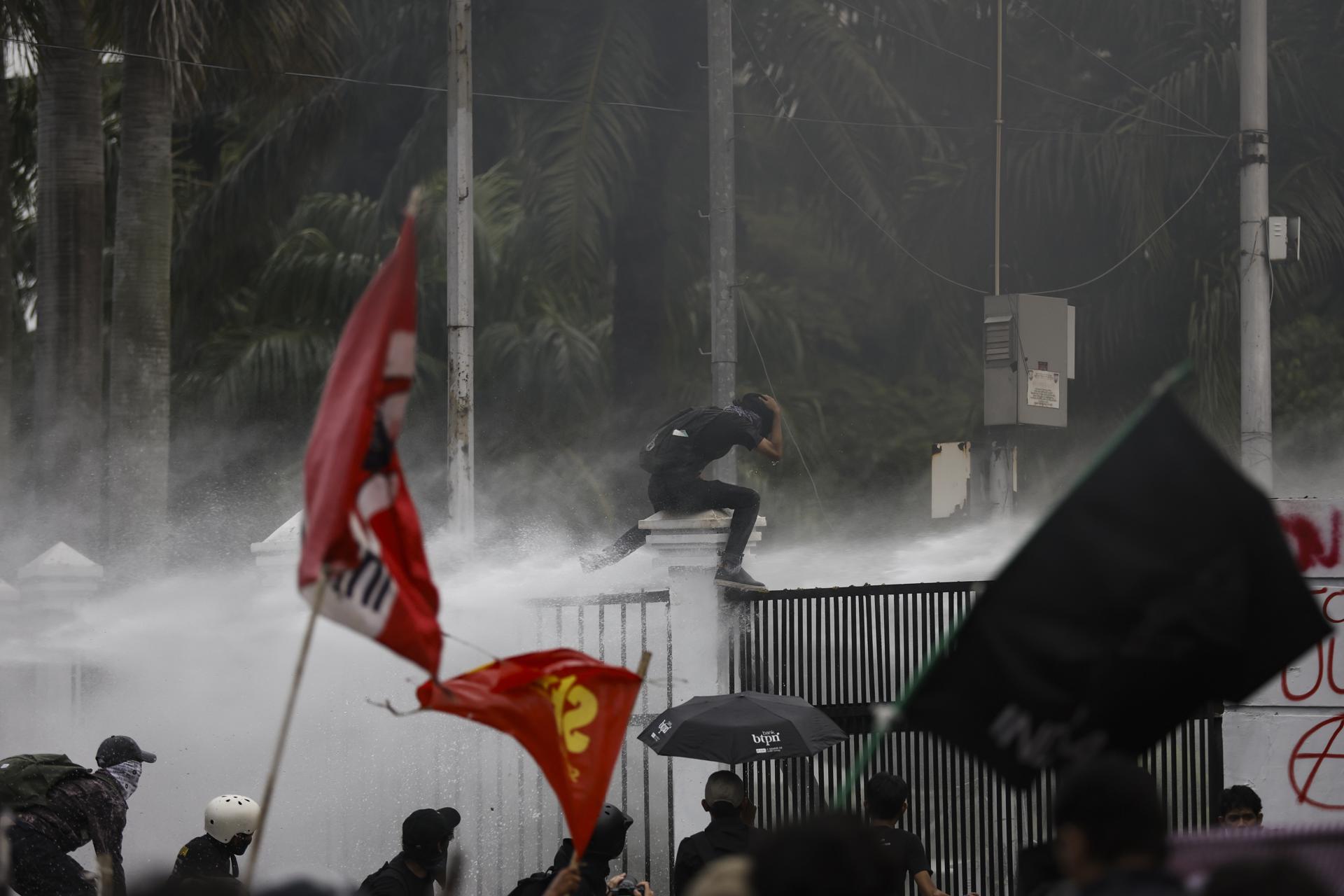 JAKARTA (Indonesia), 27/03/2025.- Protesters react as the Indonesian police spray water to disperse them during a protest against the country's newly passed military law outside of the parliament building in Jakarta, Indonesia, 27 March 2025. Hundreds of activists staged a rally against the new bill that would expand the role of the military, allowing officers to take up civilian posts. (Protestas) EFE/EPA/MAST IRHAM
