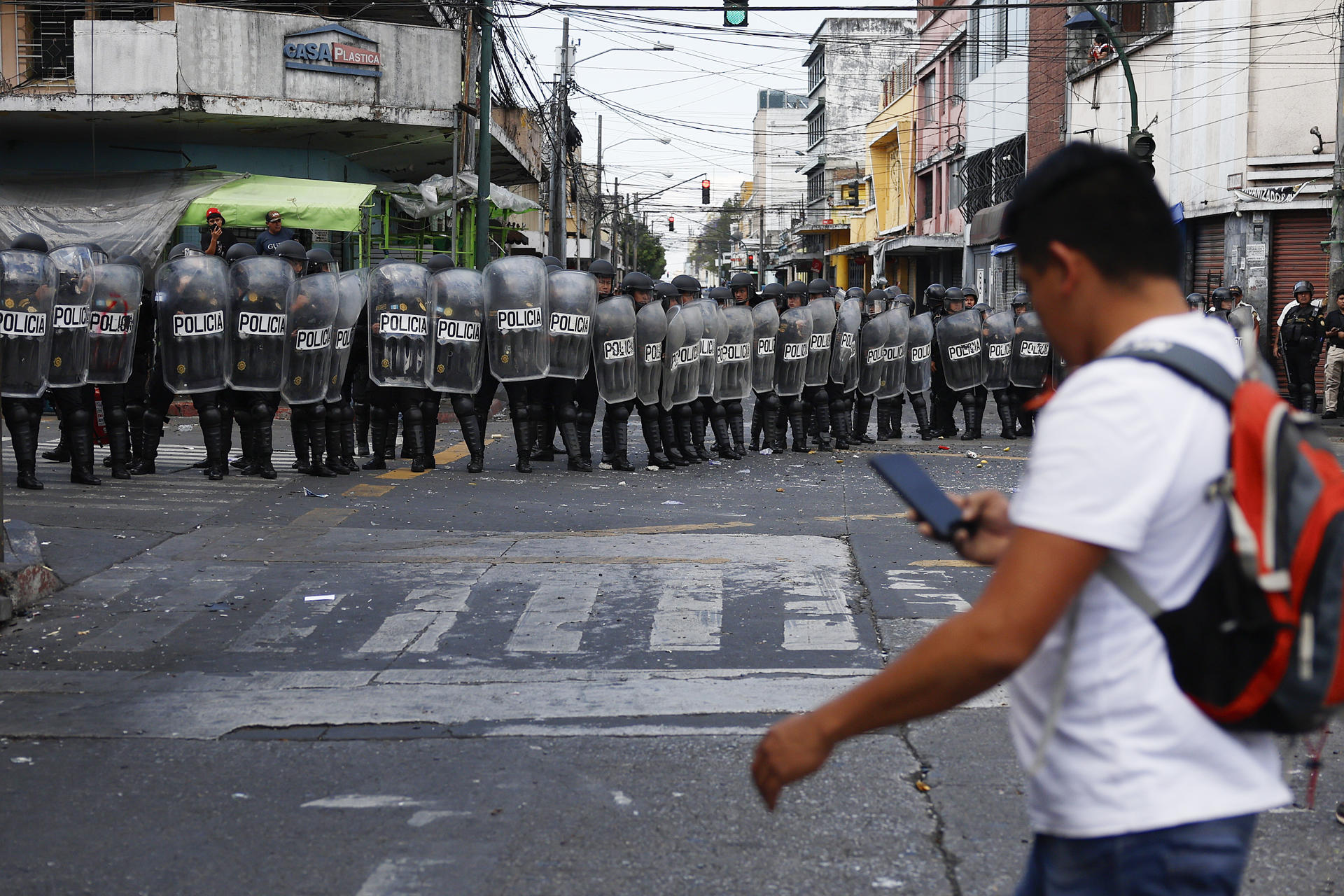 Una persona camina frente a una formación de policías durante una manifestación este 19 de marzo de 2025, en Ciudad de Guatemala (Guatemala). EFE/ David Toro