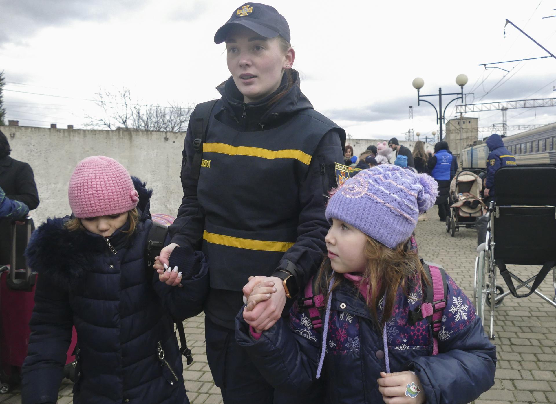 Una psicóloga militar lleva de la mano a dos niñas evacuadas cerca de la línea del frente en las áreas de Donetsk y Dnipropetrovsk en una estación de tren en Mukachevo, Ucrania, en una imagen del 17 de marzo de 2025. EFE/EPA/IGOR TKACHENKO