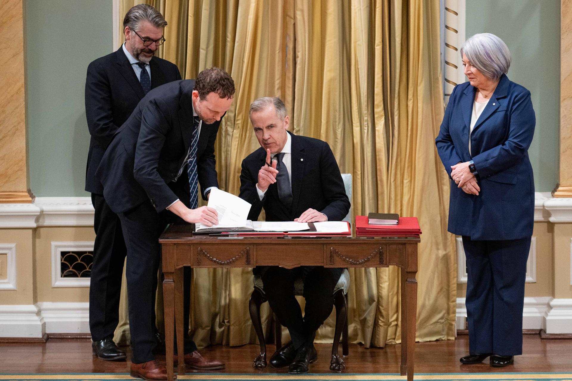 El primer ministro canadiense, Mark Carney (c), nuevo líder del Partido Liberal, firma el juramento como primer ministro de Canadá en el Rideau Hall de Ottawa (Canadá). EFE/EPA/SPENCER COLBY