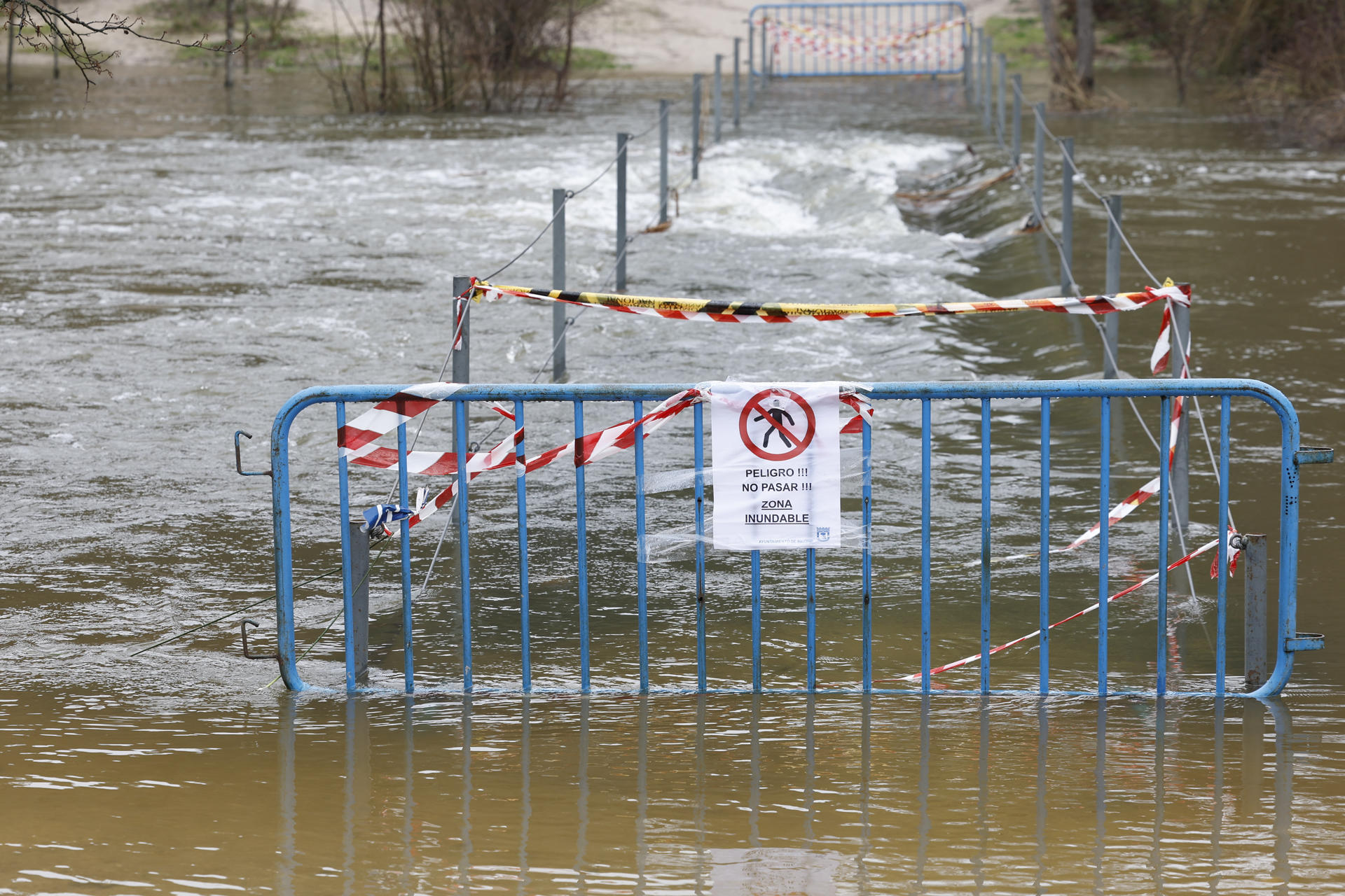 Vista de una pasarela que prohíbe el paso sobre el río Manzanares en El Pardo, Madrid este lunes tras las fuertes lluvias que ha dejado la borrasca Laurence que llega a España este lunes con más lluvias repartidas por amplias zonas de la península y que afectarán especialmente a la mayor parte de la mitad suroeste peninsular. EFE/ Chema Moya