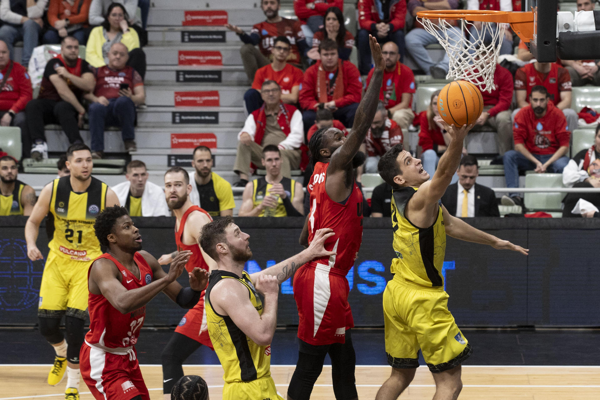 El base de Falco Vulcano Zoltan Perl (d) lanza a canasta ante la presión del alero cubano de UCAM Murcia Howard Snat-Roos (2d), durante el cuarto partido del Top 16 de la Liga de Campeones en el Palacio de los Deportes de Murcia. EFE/Marcial Guillén