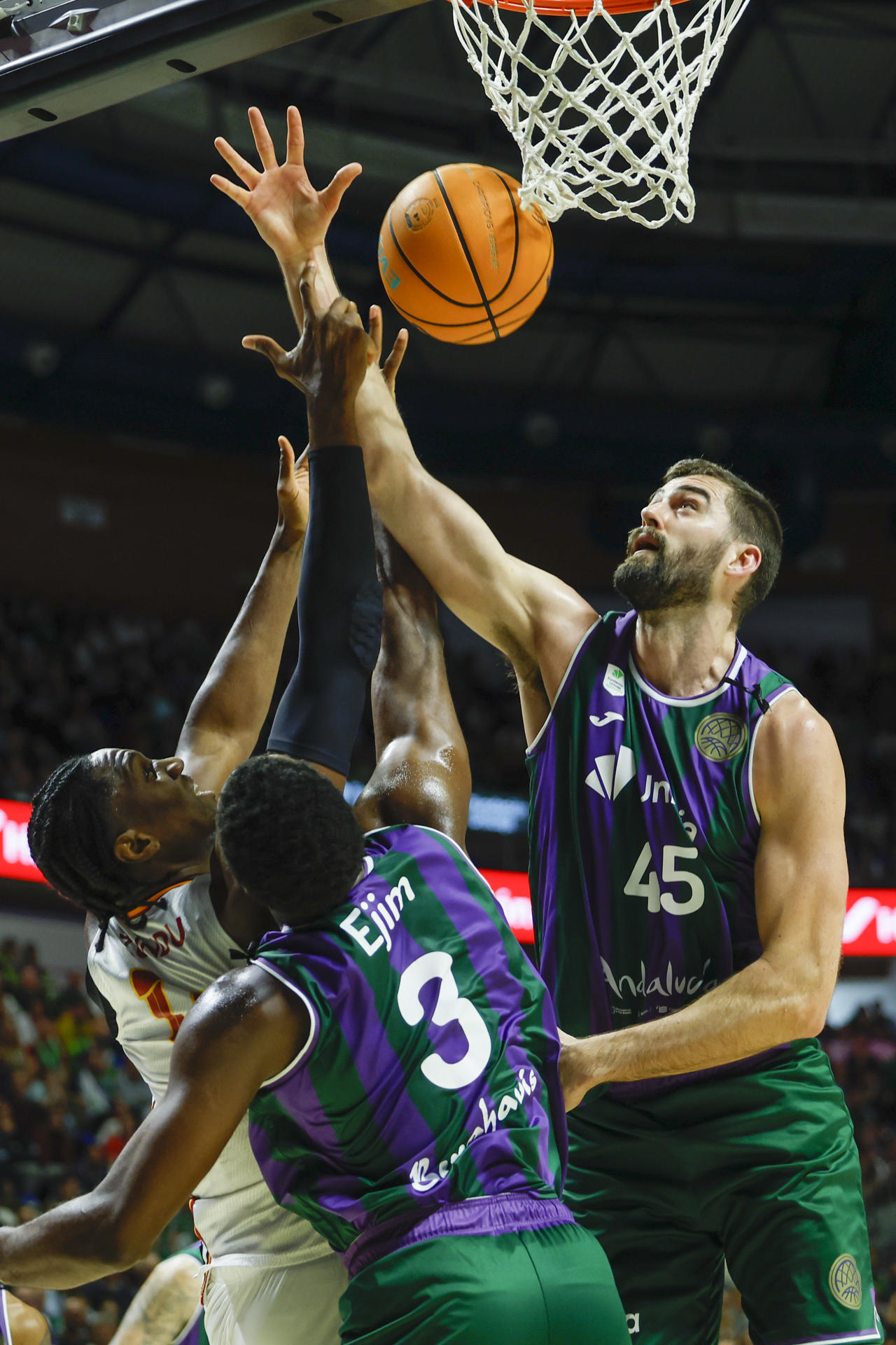 Los jugadores de Unicaja David Kravish (d) y Melvin Ejim (c) luchan con el nigeriano Ebuka Izundu, del Galatasaray, durante el encuentro correspondiente a los play-off de la Liga de Campeones que se disputó en el pabellón Martín Carpena de Málaga. EFE/ Jorge Zapata.