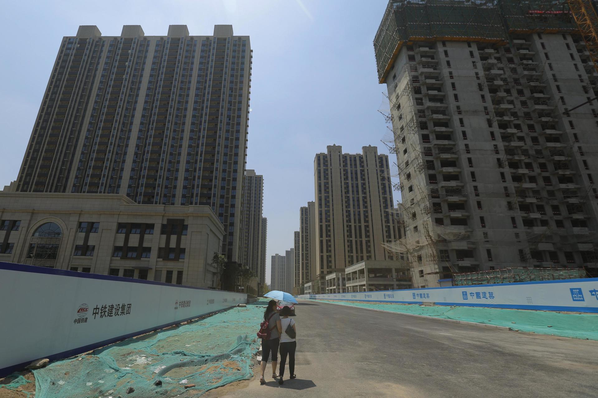 Fotografia de archivo en la que se registró a dos mujeres al pasar por un área de construcción de vivienda nueva en Pekín (China). EFE/Wu Hong