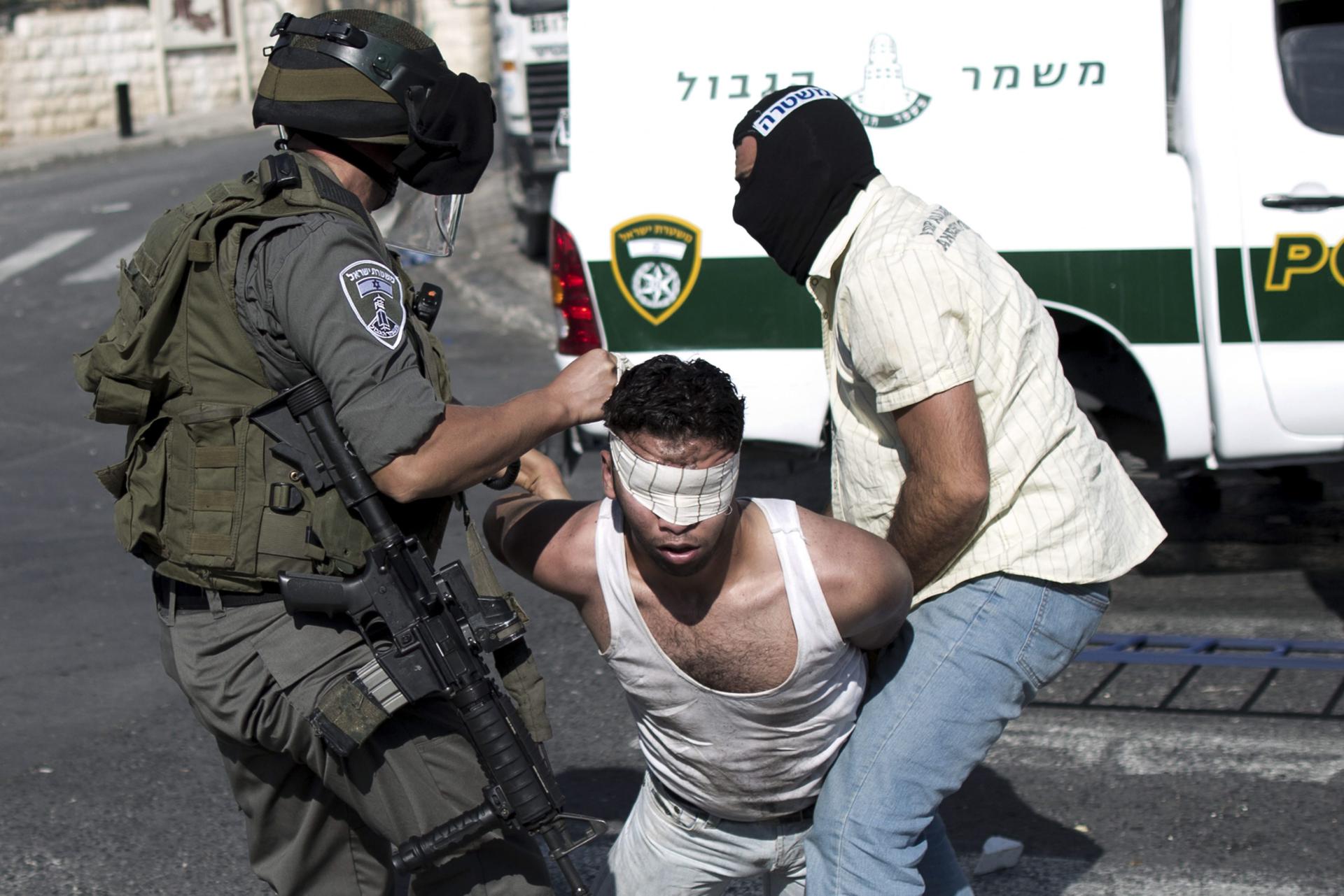 Imagen de archivo del arresto de un palestino por un soldado israelí y un policía de paisano con el rostro cubierto. EFE/Abir Sultan