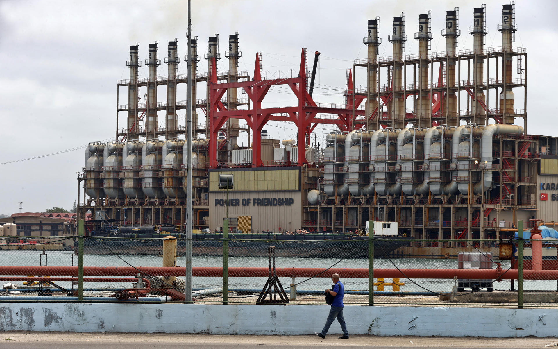 Un hombre camina frente a una planta flotante de generación eléctrica en el puerto de La Habana (Cuba), en una fotografía de archivo. EFE/ Ernesto Mastrascusa