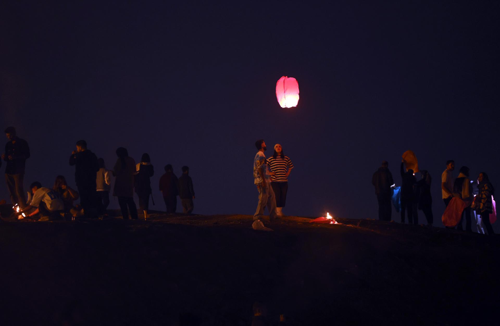 Los jóvenes sueltan linternas de deseos durante una festividad tradicional de fuego llamada 'Charshanbeh Suri' en Teherán, Irán, 18 de marzo de 2025. El festival se celebra anualmente en la víspera del último miércoles antes del Año Nuevo persa (Nowruz), que comienza el 20 de marzo de este año, marcando también el inicio de la primavera. Nowruz, que se ha celebrado durante al menos tres mil años, es la celebración más venerada en el Gran mundo persa, que incluye los países de Irán, Afganistán, Azerbaiyán, Turquía y partes del oeste de China y el norte de Irak. (Afganistán, Azerbaiyán, Turquía, Teherán) EFE/EPA/ABEDIN TAHERKENAREH