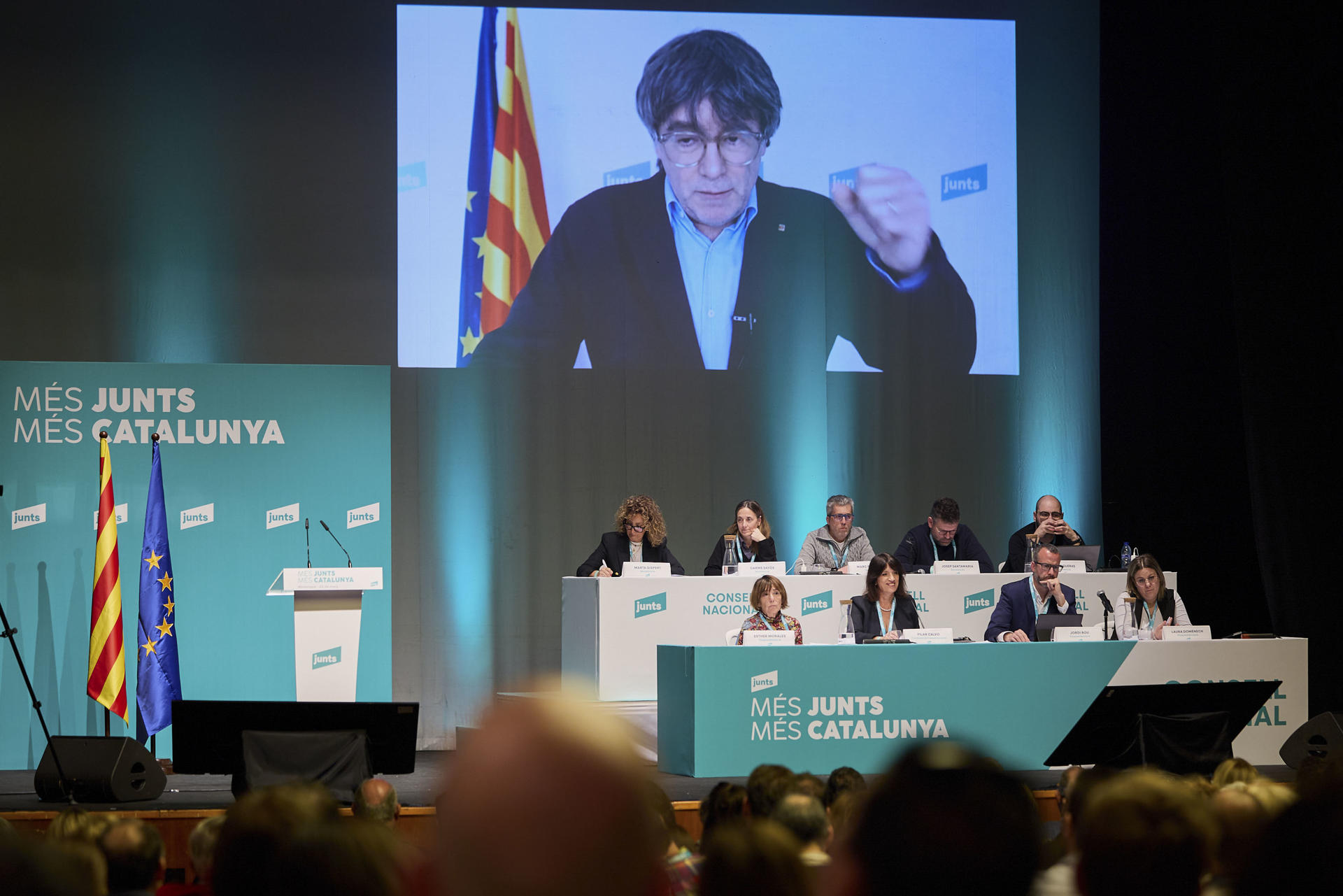 El líder de Junts per Catalunya (JxCat), Carles Puigdemont, interviene por videoconferencia en la reunión del consell nacional del partido, este sábado en Mollerussa (Lleida). EFE/Alex López