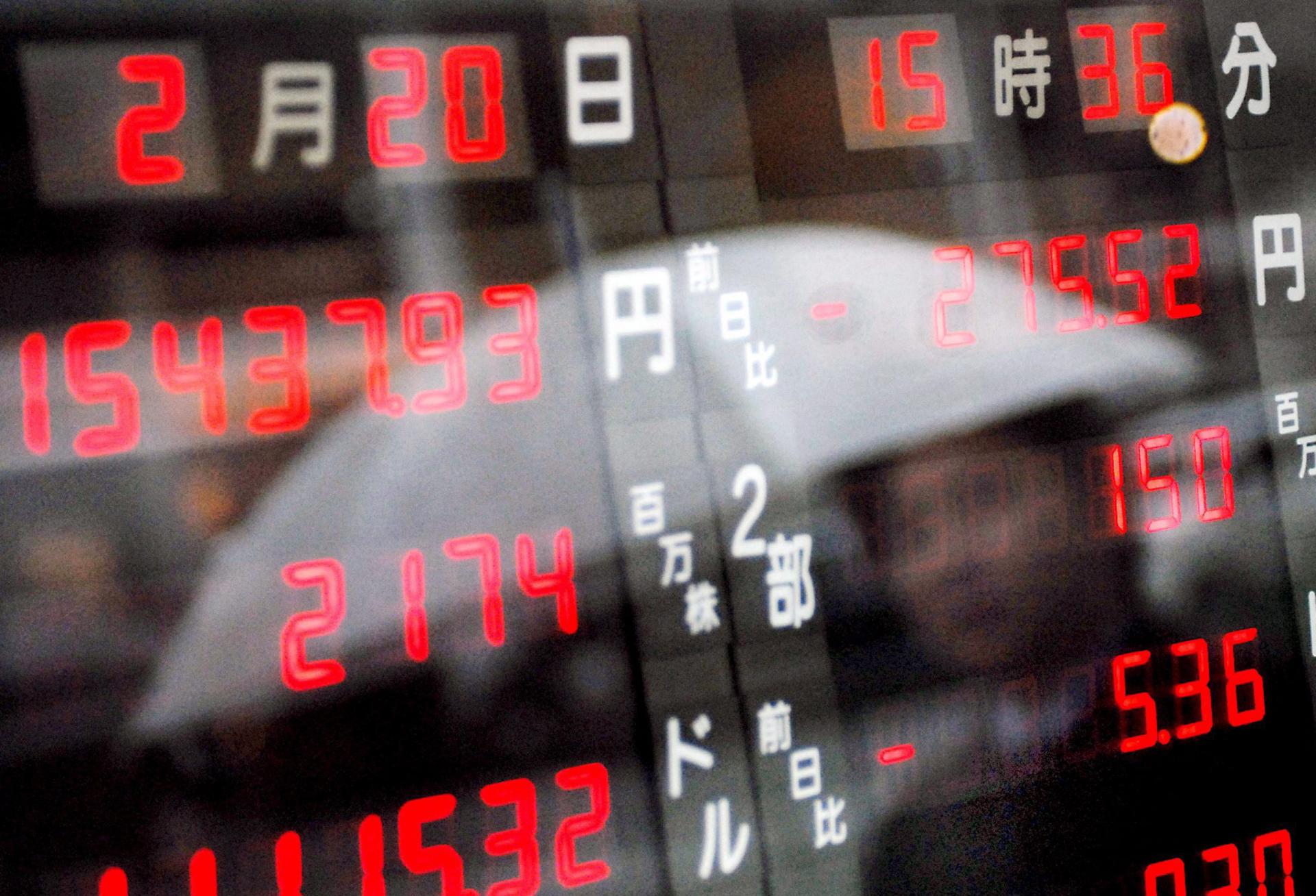 Fotografía de archivo en la que se registró el reflejo de un hombre frente una pantalla que muestra el índice Nikkei de la bolsa de Tokio (Japón). EFE/Andy Rain