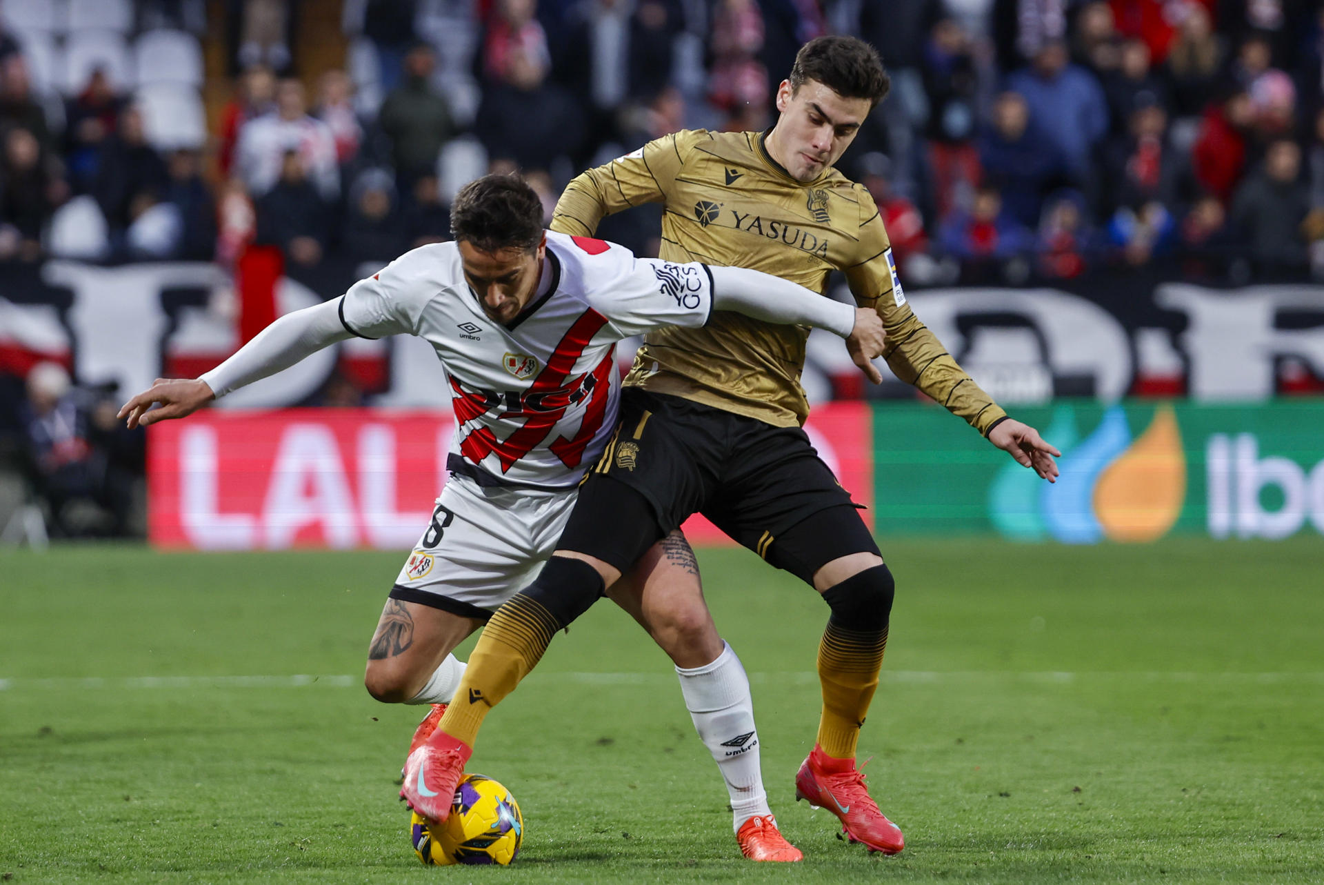 El delantero argentino del Rayo Vallecano, Óscar Trejo (i), disputa el balón ante el delantero de la Real Sociedad, Ander Barrenetxea, durante el encuentro correspondiente a la jornada 28 de Laliga EA Sports que disputaron Rayo y Real Sociedad en el estadio de Vallecas, en Madrid. EFE / Sergio Perez.
