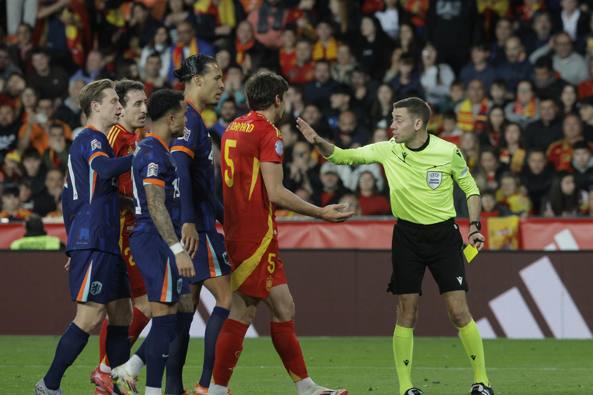 El árbitro francés Clément Turpin (d) muestra tarjeta amarilla al defensa de España Robin Le Normand (C) durante el partido de vuelta de los cuartos de final de la Liga de Naciones que las selecciones de España y Países Bajos disputan en el estadio de Mestalla, en Valencia. EFE/ Kai Forsterling