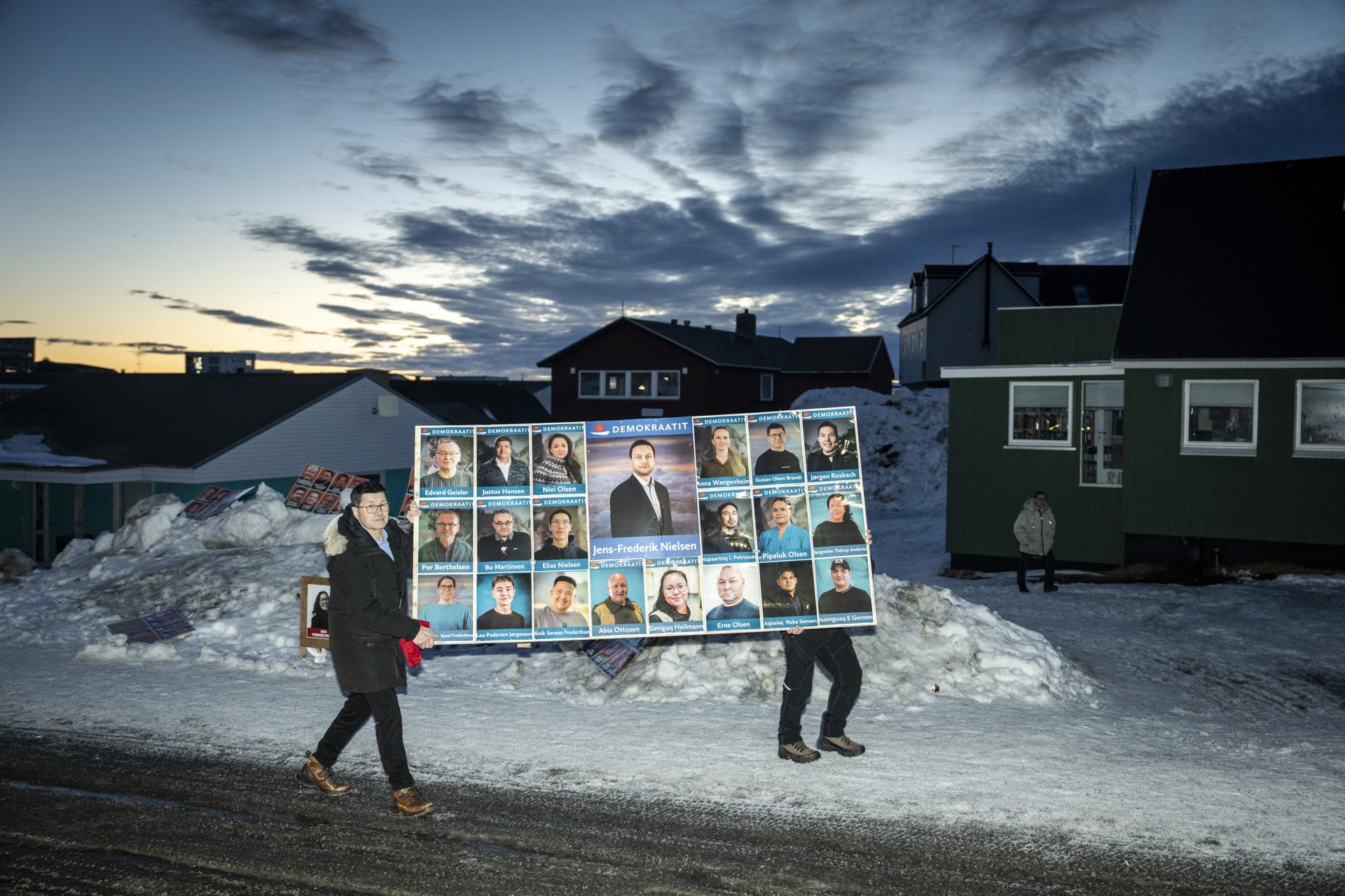 Personas llevan un cartel de campaña electoral del Partido Demokraatit y su líder Jens-Frederik Nielsen (C) frente al estadio Godthaabshallen y estación de votación durante las elecciones parlamentarias, en Nuuk, Groenlandia, 11 de marzo de 2025 (emitido el 12 de marzo de 2025). Los residentes de Groenlandia votaron el 11 de marzo para elegir a 31 miembros del Inatsisartut, el parlamento groenlandés, siendo el partido Demokraatit el que se destacó como el partido líder en las elecciones de Groenlandia con el 29.9 por ciento de los votos. Elecciones, Groenlandia EFE/EPA/MADS CLAUS RASMUSSEN DINAMARCA FUERA