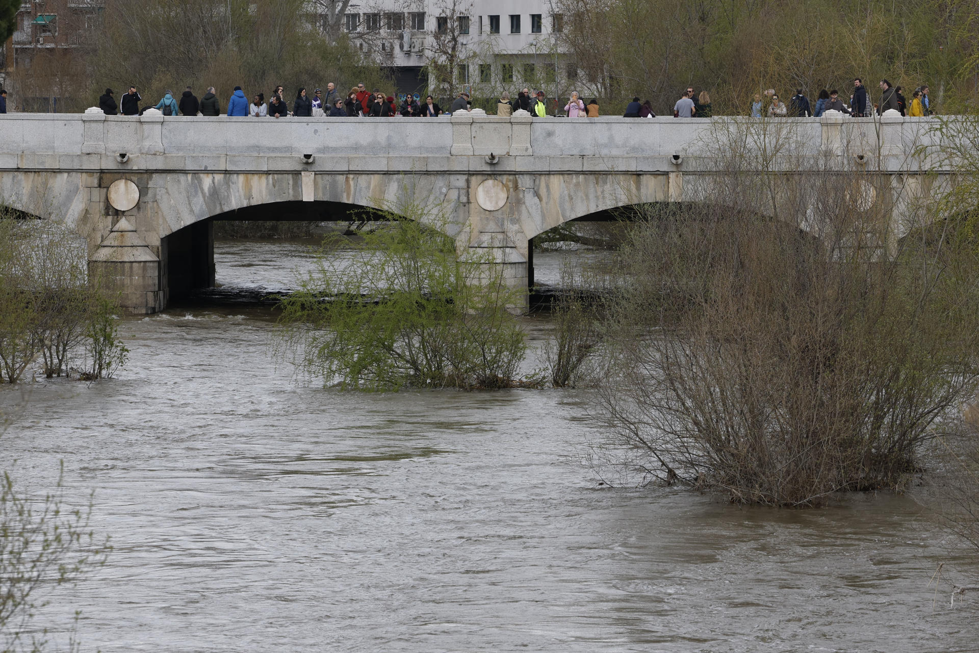 Varias personas observan el caudal del río Manzanares a su paso por Madrid, este domingo. EFE/Javier Lizón