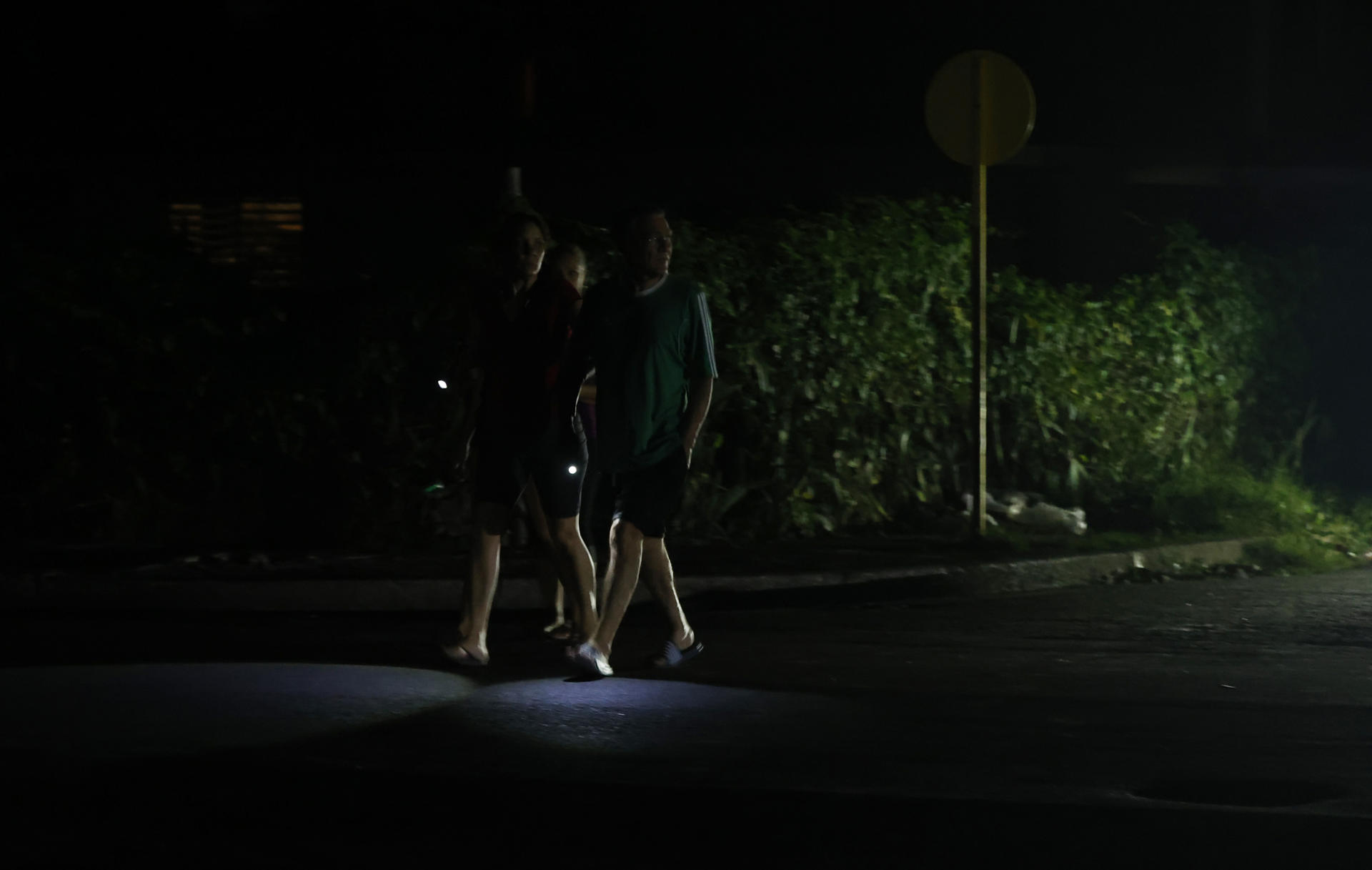 Personas caminan por una calle sin luz este sábado, en La Habana (Cuba). EFE/ Ernesto Mastrascusa